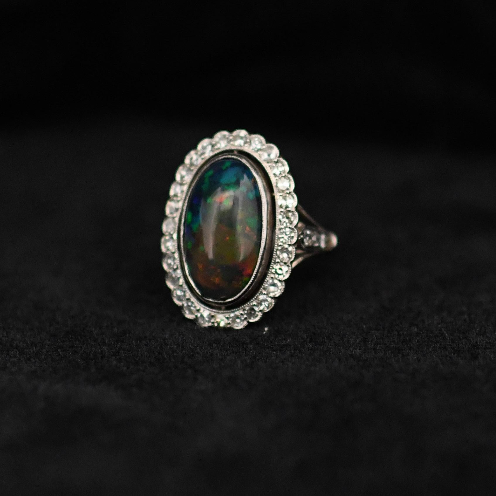 Lassen Sie sich von der exquisiten Schönheit dieses edwardianischen Opal-Cabochon-Rings verzaubern. Er präsentiert einen atemberaubenden 6,19-karätigen Opal mit einem faszinierenden Harlekin-Muster. Dieser handgefertigte Platinring besticht durch