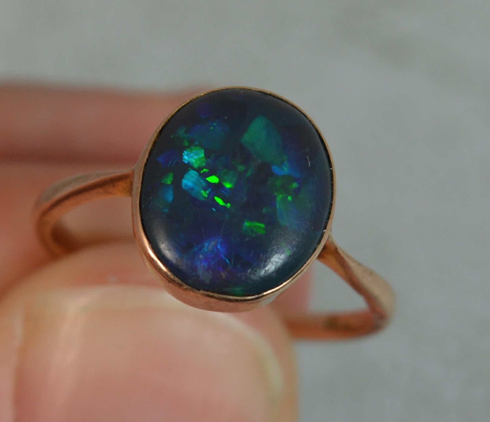 A rare Edwardian era 9ct gold and natural black opal solitaire ring.
SIZE ; M 1/2 UK, 6 1/2 US
The opal to measure 9.8mm x 11.2mm approx and set into a fine plain gold bezel setting. Fine colourful example.
Circa 1910.

CONDITION ; Good for age.