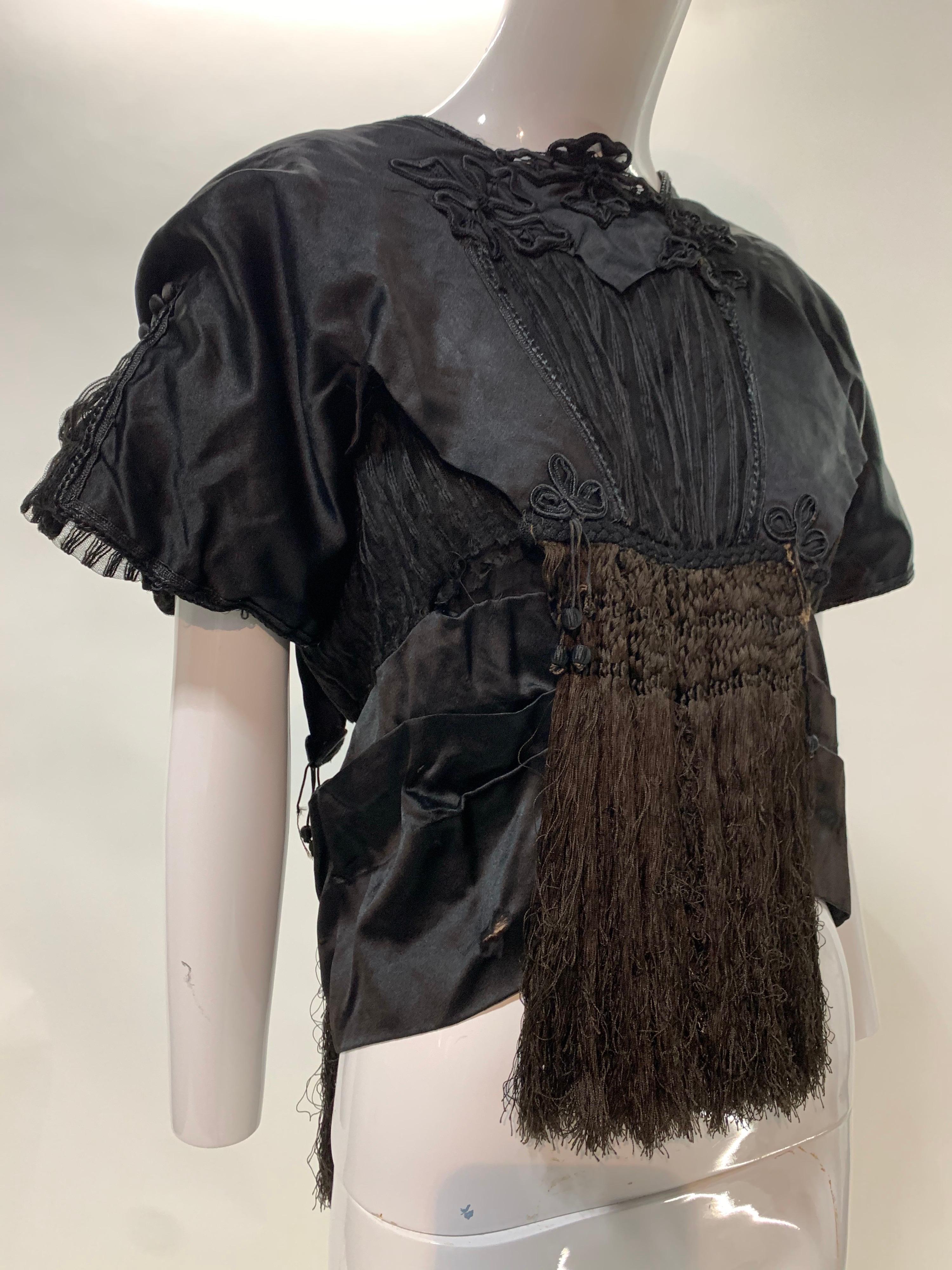 Eine umwerfende edwardianische Bluse aus schwarzem Seidensatin mit extravaganten Seidenfransen in der vorderen und hinteren Mitte, Spitzenbesatz und gerafften Cap-Ärmeln. Krawatte in der hinteren Mitte. Großzügige Verschönerung bei jedem Blick.