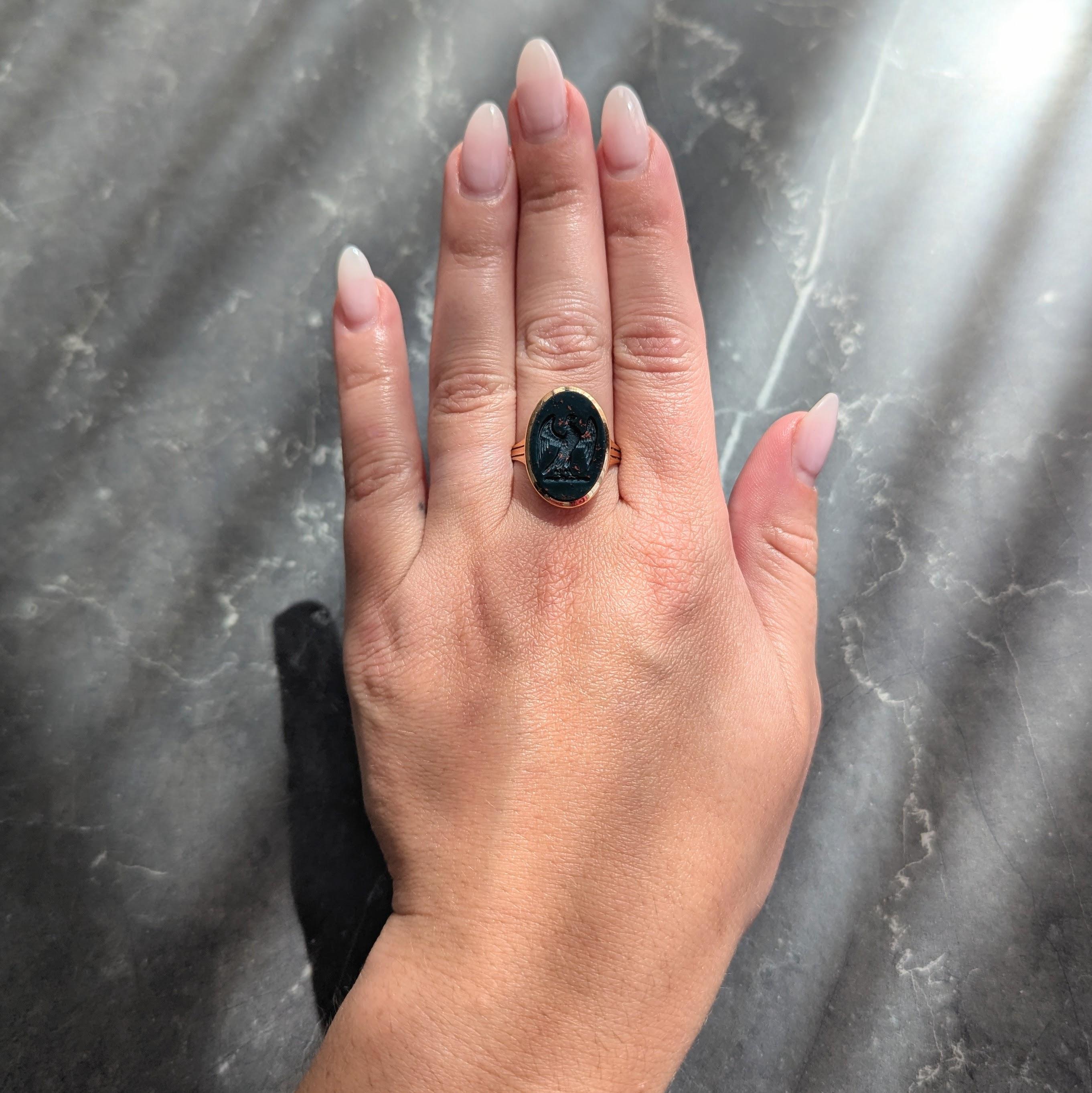 Centratura di una tavoletta di pietra sanguigna di forma ovale che misura 13,0 x 19,0 mm
Colore verde scuro opaco e bluastro con screziature arancione rossastro.
Incisione di un'aquila araldica appollaiata ad ali spiegate.
Lunetta incastonata e