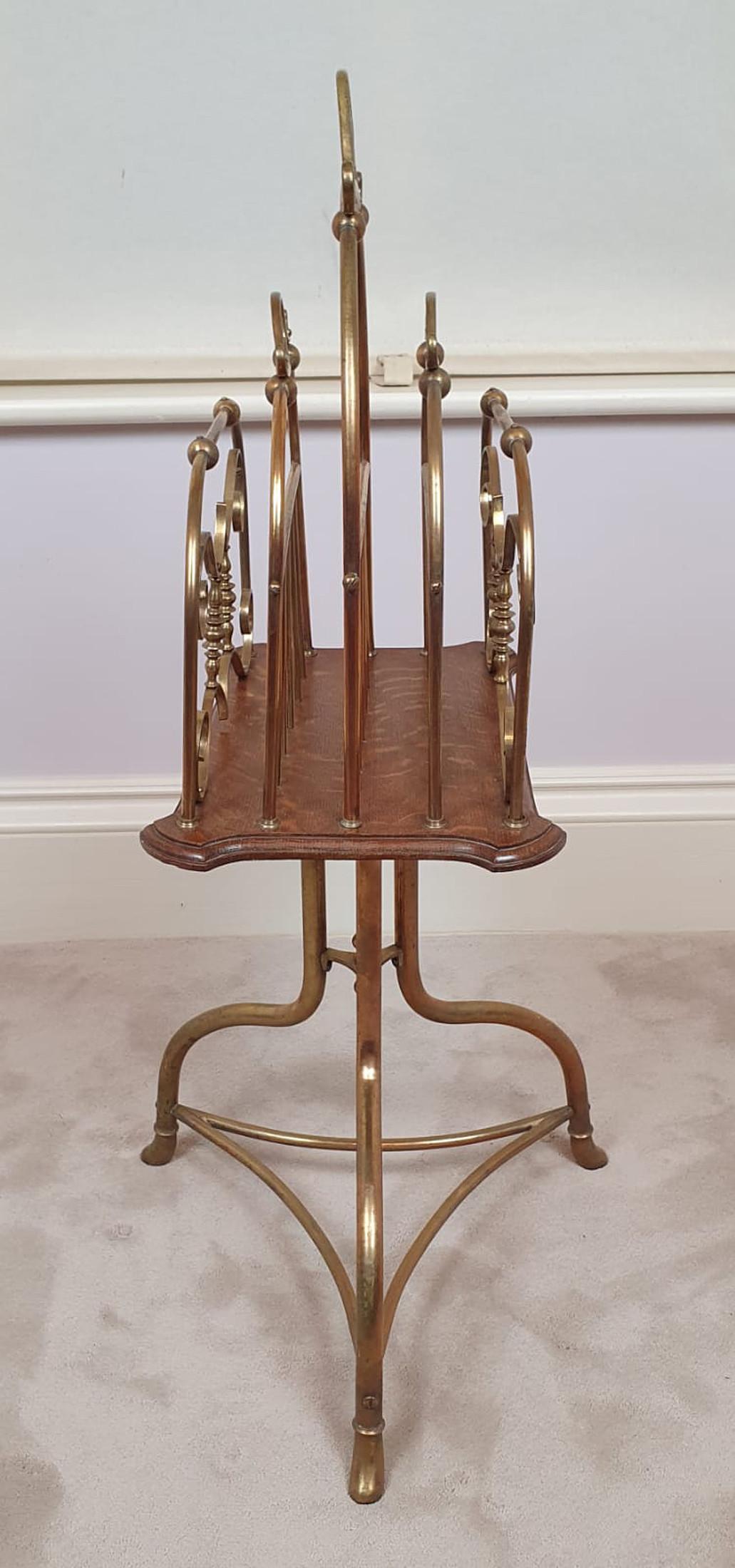 Edwardian brass and oak magazine stand. The brass scroll handle above four brass divider sections raised on moulded and shaped oak section supported on brass tripod base joined with concave stretcher.