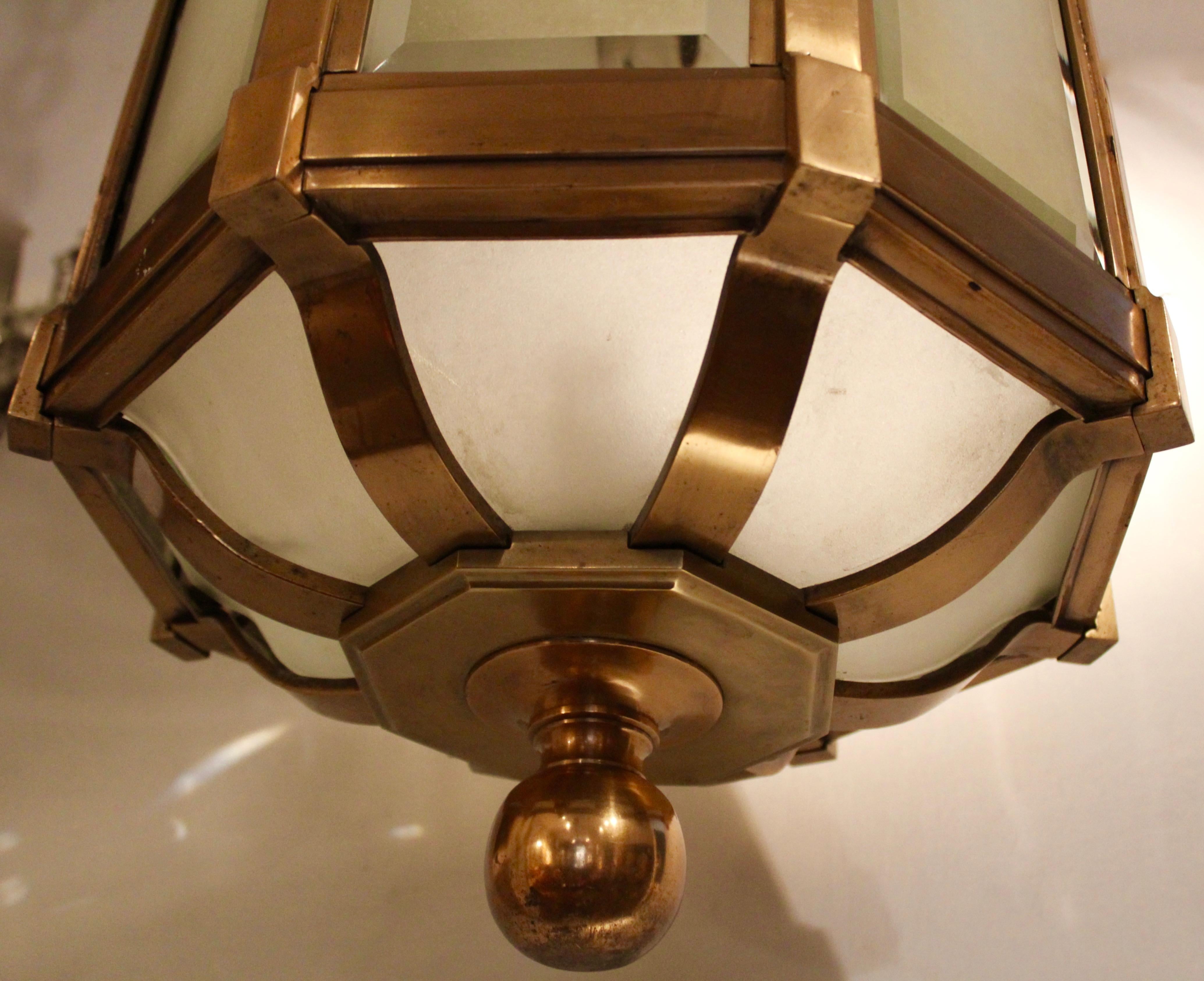 An Edwardian bronze and frosted glass hall lantern, circa 1910. The hexagonal lantern composed of bevelled frosted glass panes within a brass frame, terminating in a bronze knop. With original ceiling rose and chain, not wired.