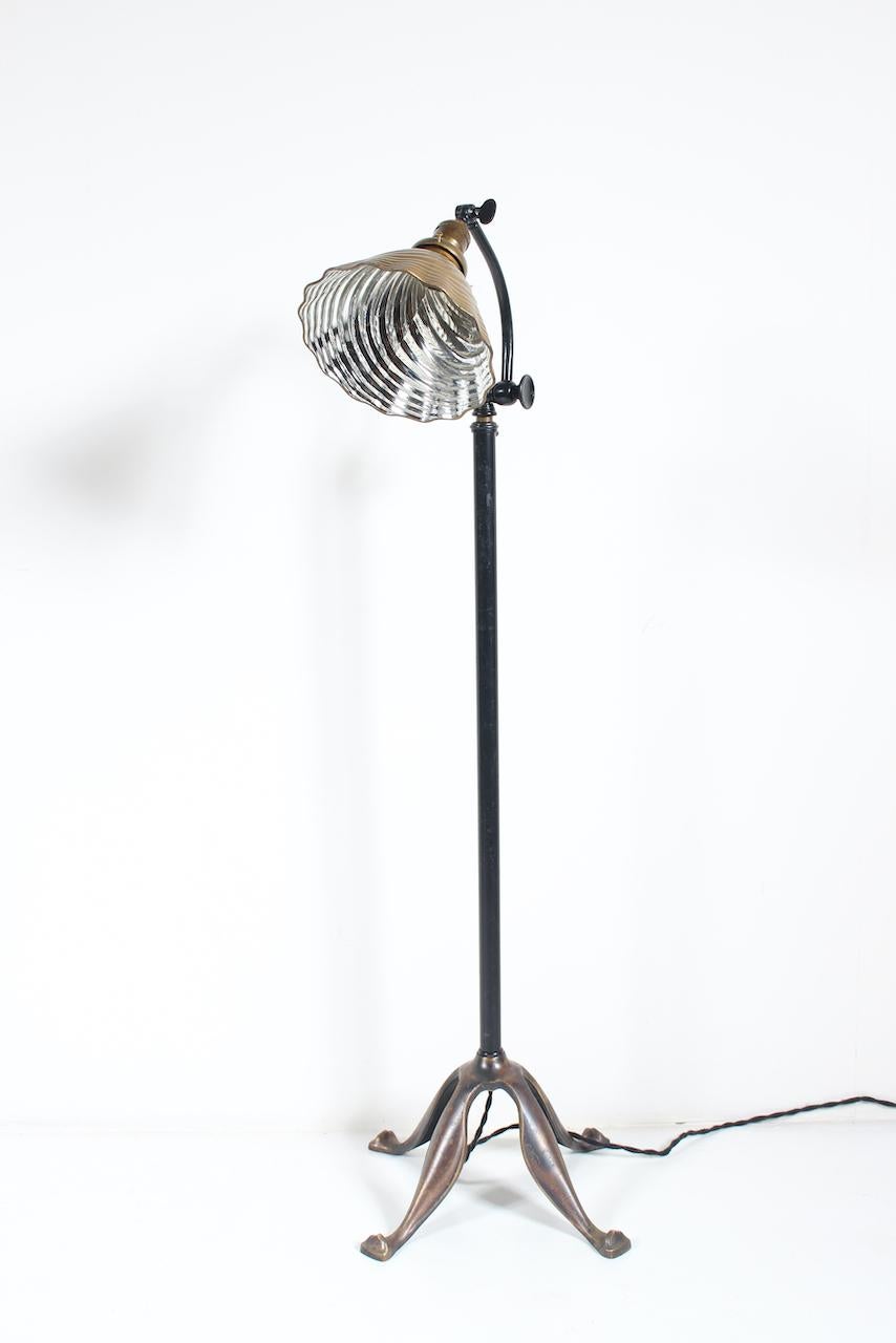 Early 1900s bronze, brass and enameled brass articulating reading floor lamp. Small footprint. Featuring an adjustable (45H-66H) Brass and Black enameled Brass Stem, Latch operates Stem height, round Knob to top Stem adjusts curved Arm, Knob to side
