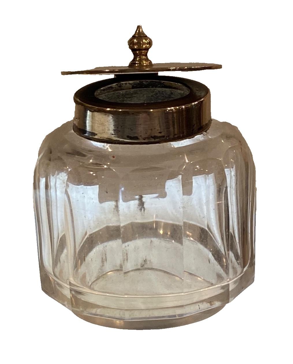Glass ink well with a sterling silver hinged top, 
bearing English hallmarks: 
letter date for 1902 & maker’s mark “J.D. W.D.”- 
By James Deakin & Sons (John & William F Deakin)
English hallmark for sterling silver 

Height: 6 cm. 
In good condition 