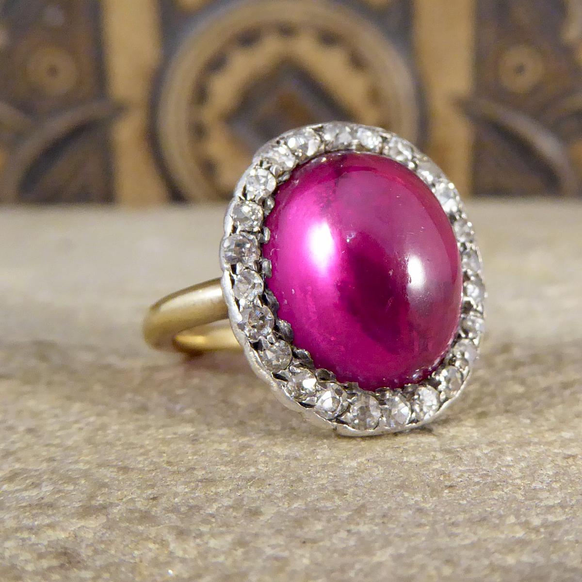 A classic Edwardian cluster ring, handmade with quality craftsmanship. It has been modelled in 18ct Yellow Gold and Silver with markings on the inner band (faded). The design features a Cabochon Crown Lab grown Ruby in the centre with a surround of