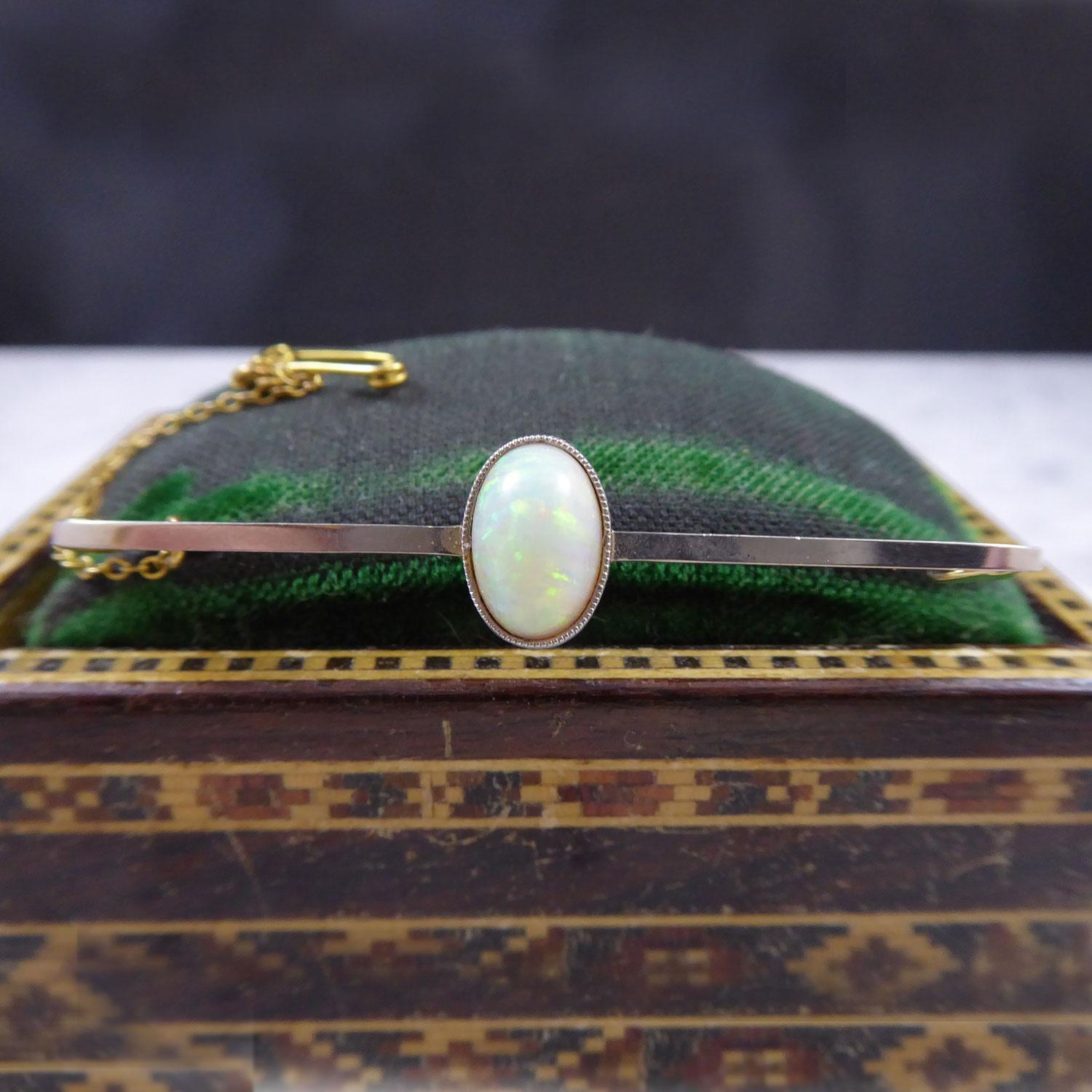 A neat and simply styled bar brooch, the mainstay of many a classic wardrobe.  This lovely example dates from the Edwardian era and features a cabochon cut opal white in colour and with flashes of turquoise and shades of orange througout.  The opal