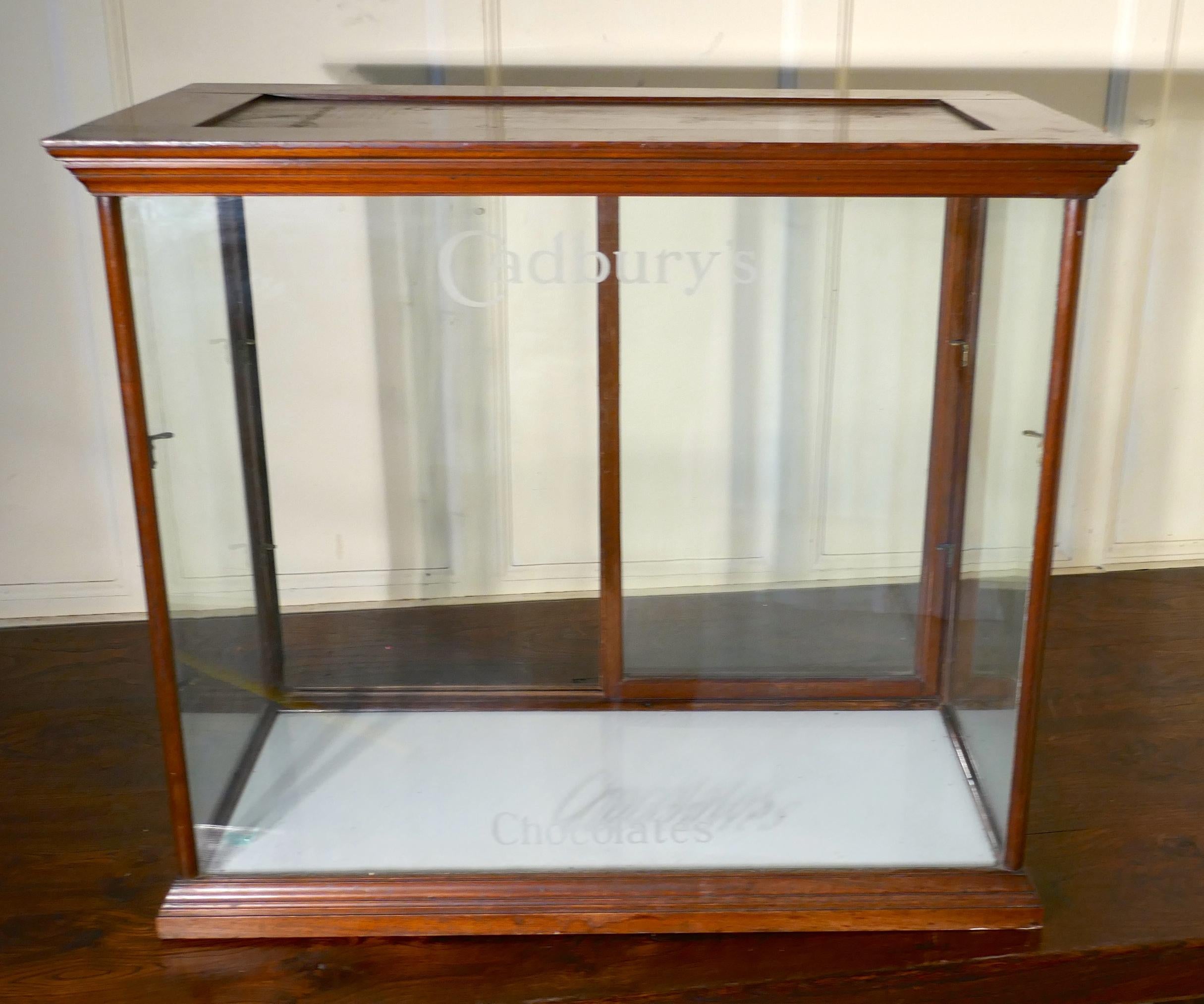 Edwardian Cadbury's Thekenaufsatz Süßwarengeschäft Vitrine

Diese verglaste Vitrine ist aus Mahagoni, das Glas hat geätzte Schriftzüge auf der Vorderseite der Schränke sagen Cadbury's an der Spitze und Pralinen an der Unterseite

Der Schrank hat