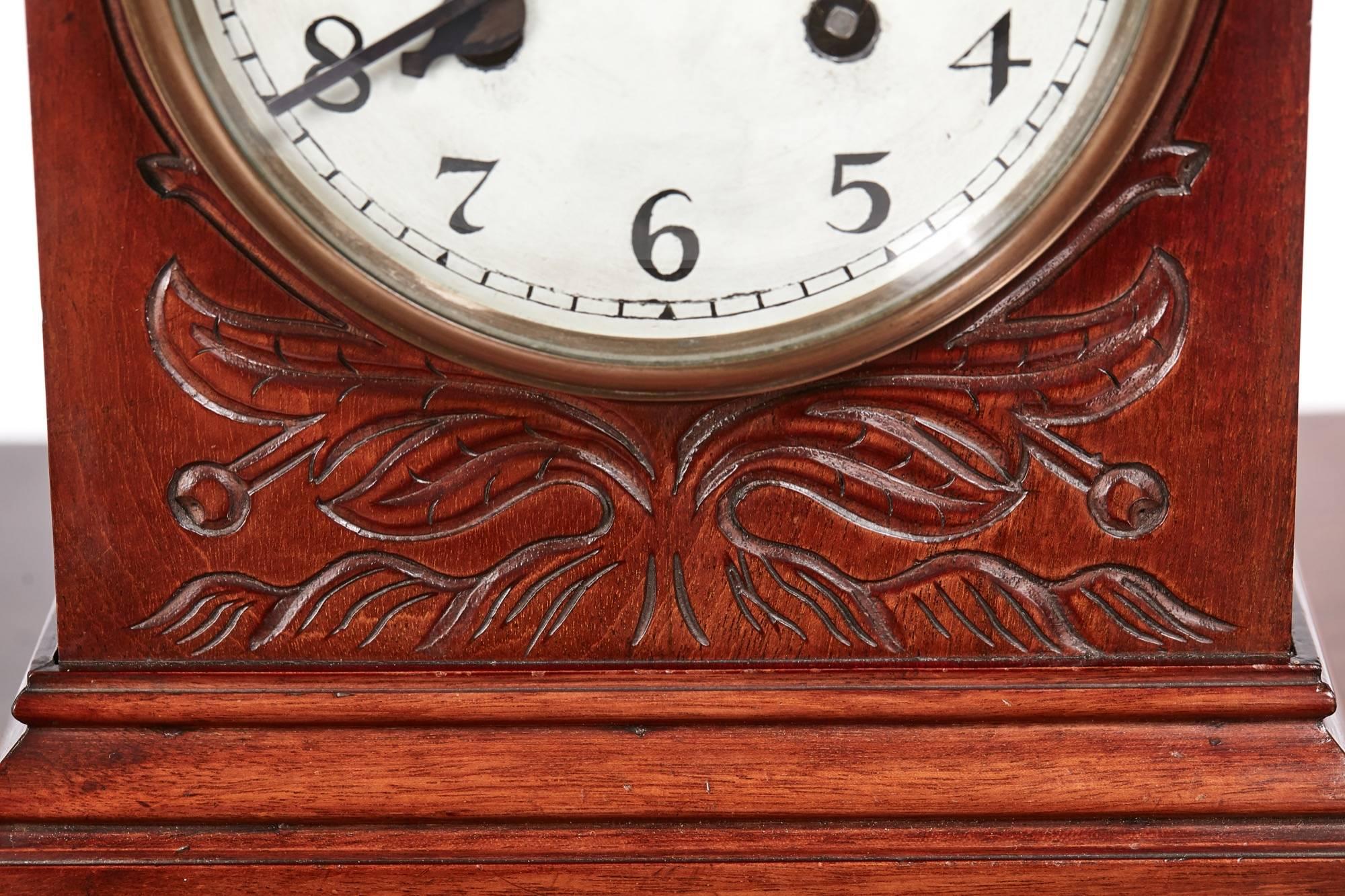 Edwardian carved mahogany mantel clock, with an arch top, well carved mahogany case with a stepped base standing on brass ball feet, enamel dial has a brass bezel and convex bevel edge glass, eight day movement striking the hour and halves on a