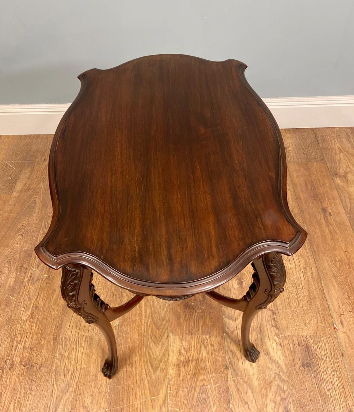 Table d'appoint raffinée d'époque édouardienne avec pieds cabriole sculptés
Circa 1910
Le tablier est richement sculpté de motifs d'acanthe enroulés, centrés par un cartouche de coquillages stylisés.
Les quatre pieds cabriole présentent une courbure