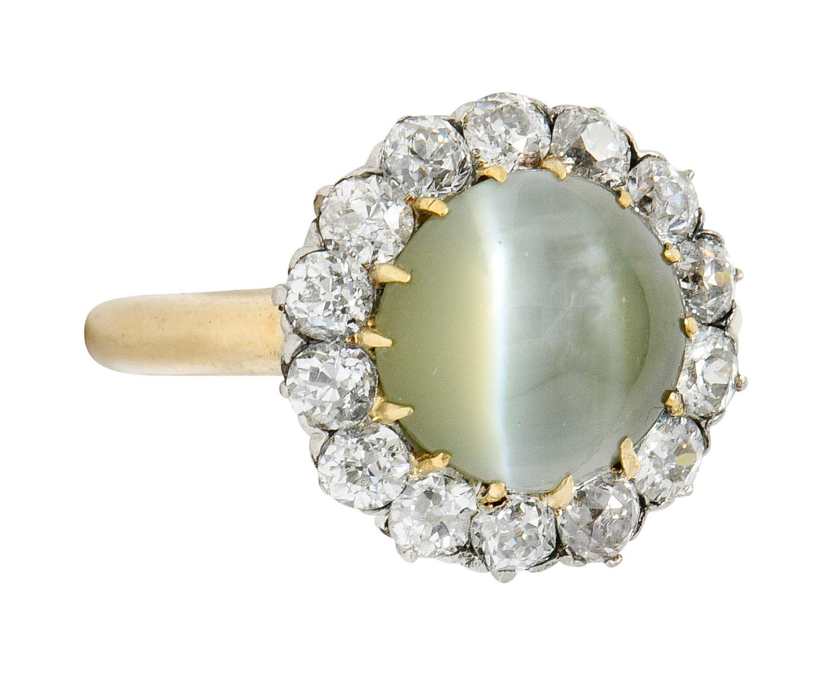 Centering a 9.3 mm round cat's eye chrysoberyl cabochon

Translucent slightly yellowish-green with a sharp white eye

Surrounded by old mine cut diamonds, set in platinum, weighing approximately 1.20 carats

Weighing approximately 1.20 carats with G