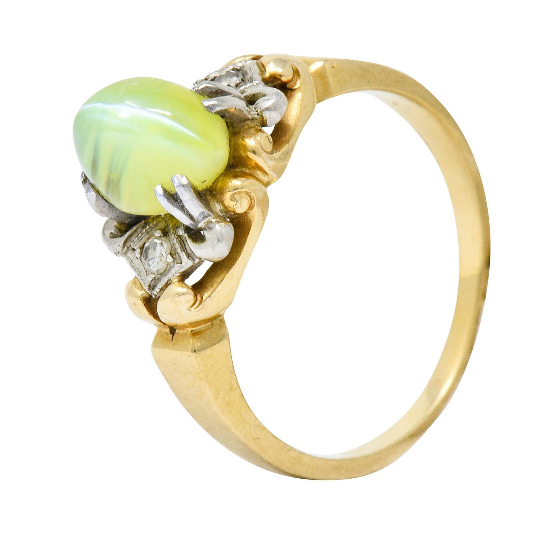 Centering a highly domed cat's eye chrysoberyl cabochon measuring approximately 7.8 x 6.0 mm

Translucent yellowish-green in color with a sharp white eye

Claw set with stylized split platinum prongs and flanked by platinum navette forms

Accented