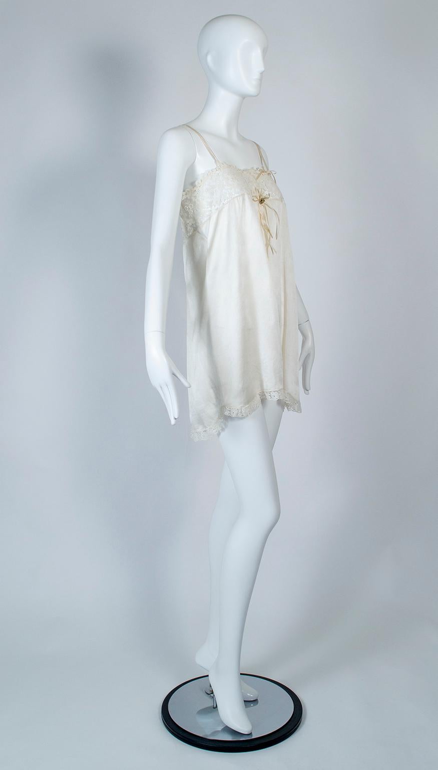 Part of a spectacular wedding trousseau, this alluring chemise features an inset lace chest threaded with a satin ribbon and ties at the left spaghetti strap. A small gold silk bouquet punctuates the center chest, flanked by loose ribbons that draw