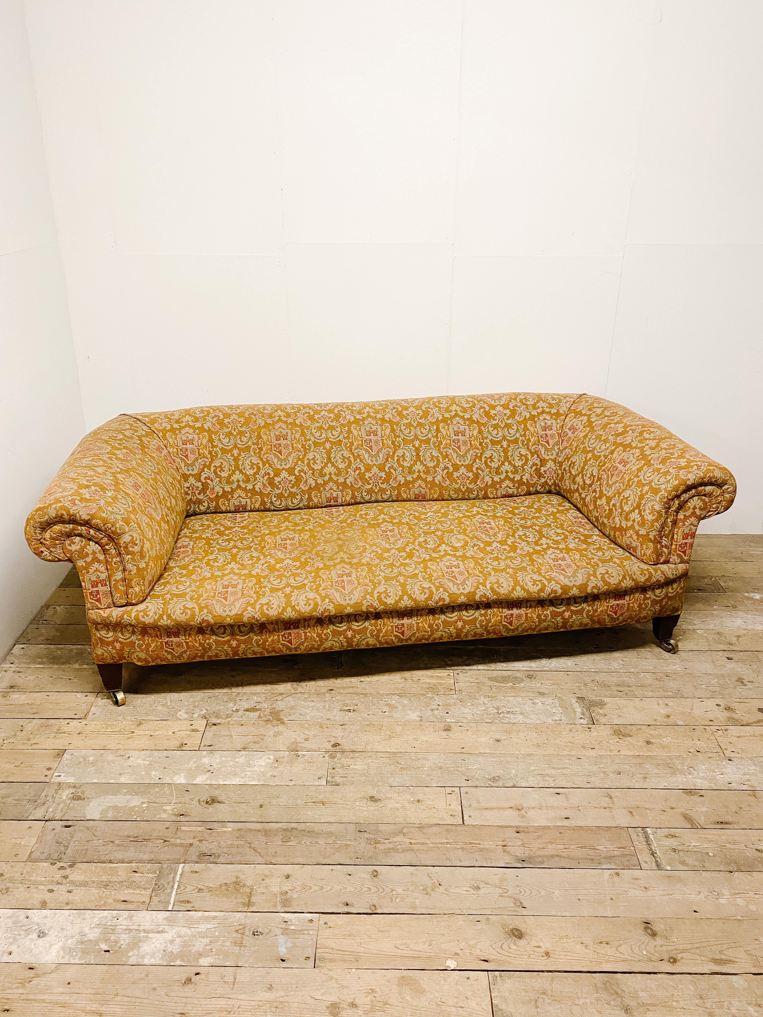 This Chesterfield style C1910 Edwardian sofa is the full package of style, comfort and a statement piece. A comfortable sofa with original upholstery complete and casters. This fabulous strong weave crest fabric has retained its beautiful colouring