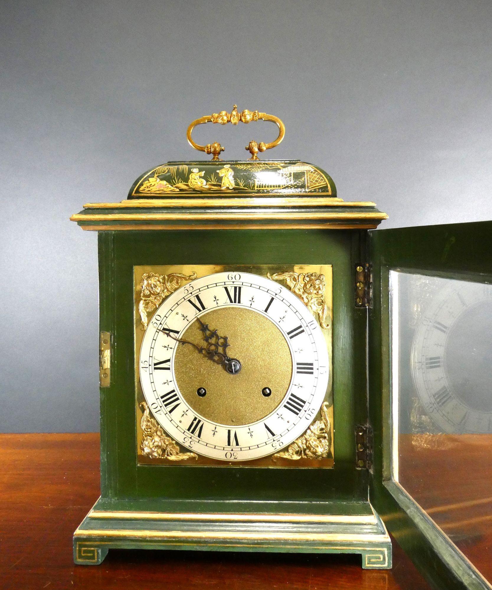 Edwardian bell top mantel clock standing on a raised plinth and resting on block feet with side viewing glasses and surmounted by a decorative carrying handle.
Beautifully decorated case with raised chinoiserie decoration on a green ground.
Brass