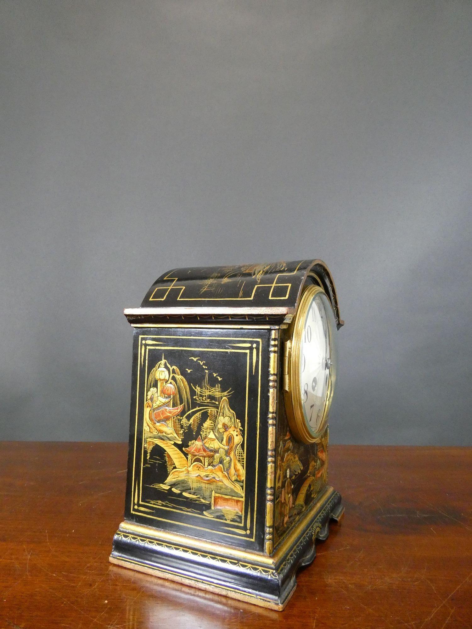 Edwardian mantel clock housed in a break arch case with raised chinoiserie decoration on a black ground and resting on a wavy plinth.
Brass bezel opening to the silvered dial with engine turned centre, Arabic numerals and original ‘blued’ steel