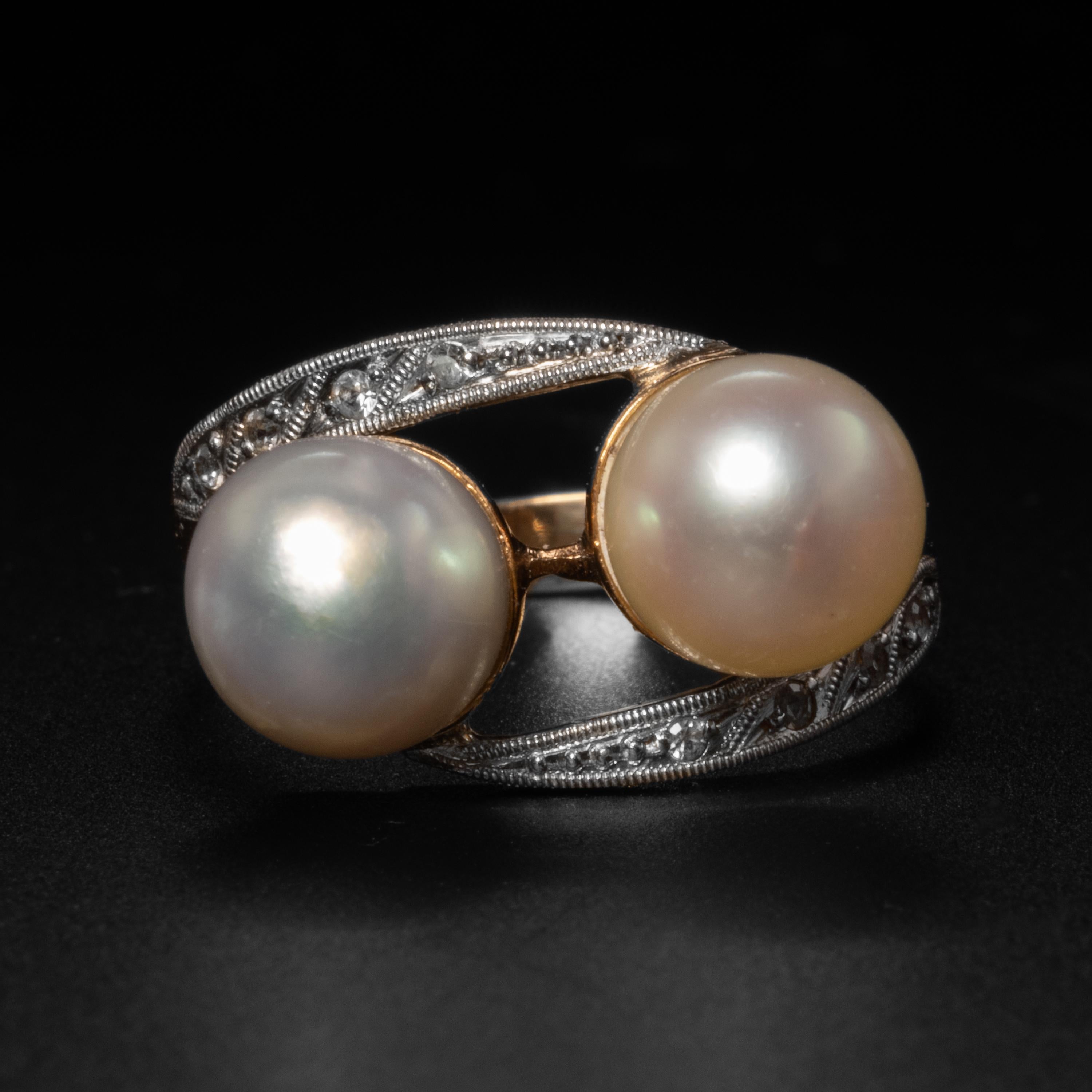 This graceful and perfectly proportioned 18K yellow gold, platinum, and diamond ring hosts a pair of luminous cultured saltwater Akoya pearls. The pearls measure 7.54mm and 7.64mm, so they are nearly a perfect size match. One is cream, the other