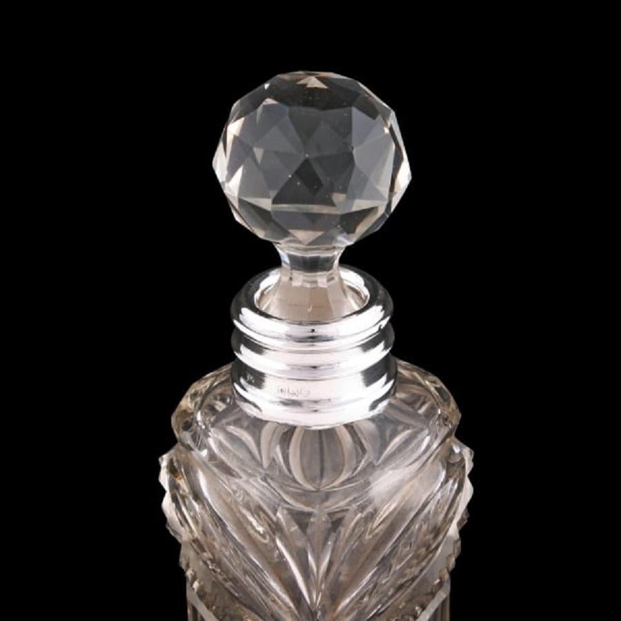 An early 20th century cut crystal perfume bottle with a sterling silver collar.

The circular bottle is thistle shaped with heavy cut decoration, a triple ring sterling silver collar and a glass stopper.

The silver collar has hall marks for