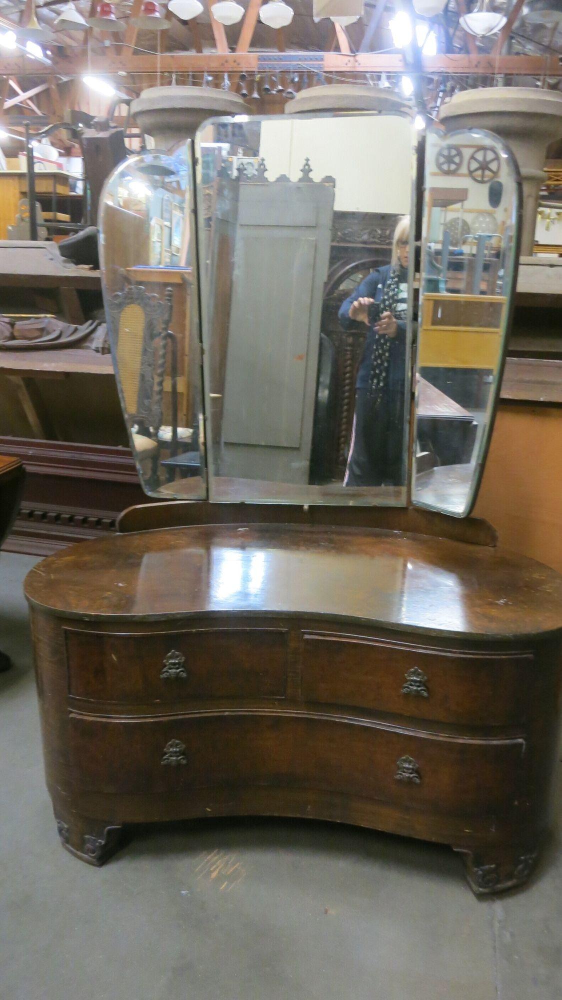 Edwardian dark-stained burlwood vanity with 3 drawers and a top trifold mirror. The vanity has a kidney shape with decorative brass pulls
