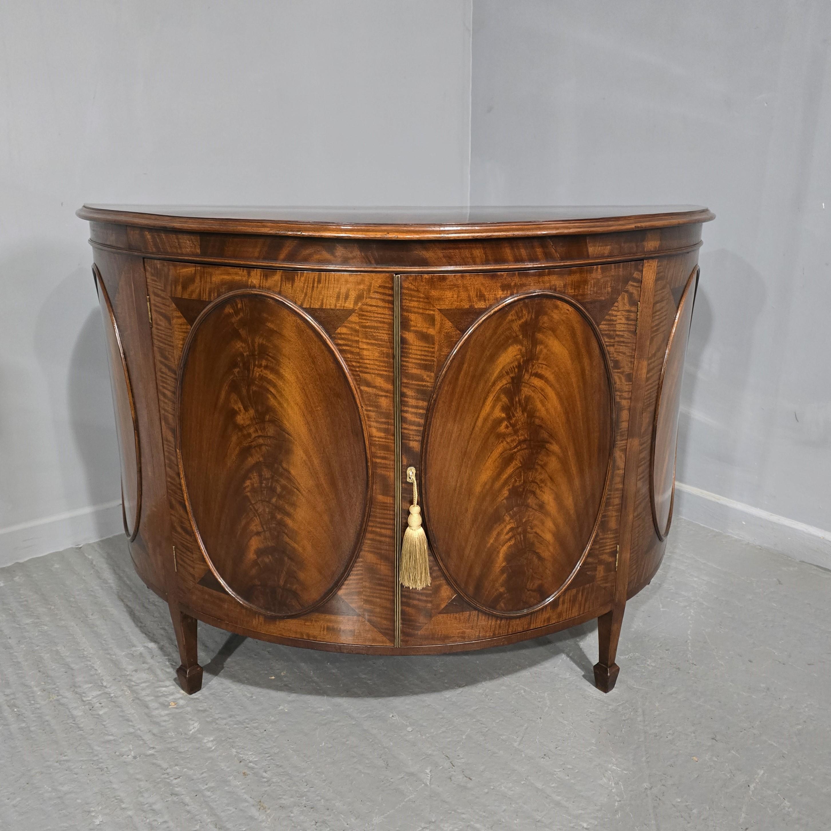 A  very nice Edwardian mahogany two door demi lune sideboard, oval panels, brass slamming strip, single shelf inside, in very good all round condition.

36