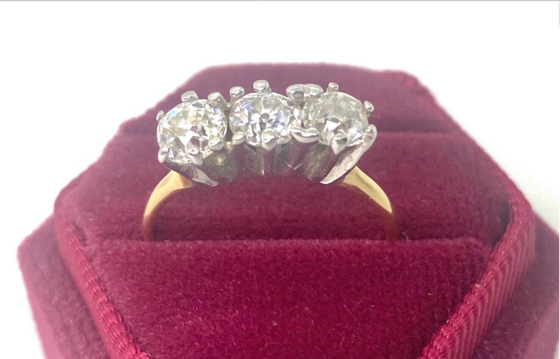 This lovely vintage three-stone diamond engagement ring features three round brilliant cut diamonds H/SI2, with an approximate total weight of 1.50 carats, all mounted in Edwardian antique claw settings. The beautiful row of diamonds is set atop in