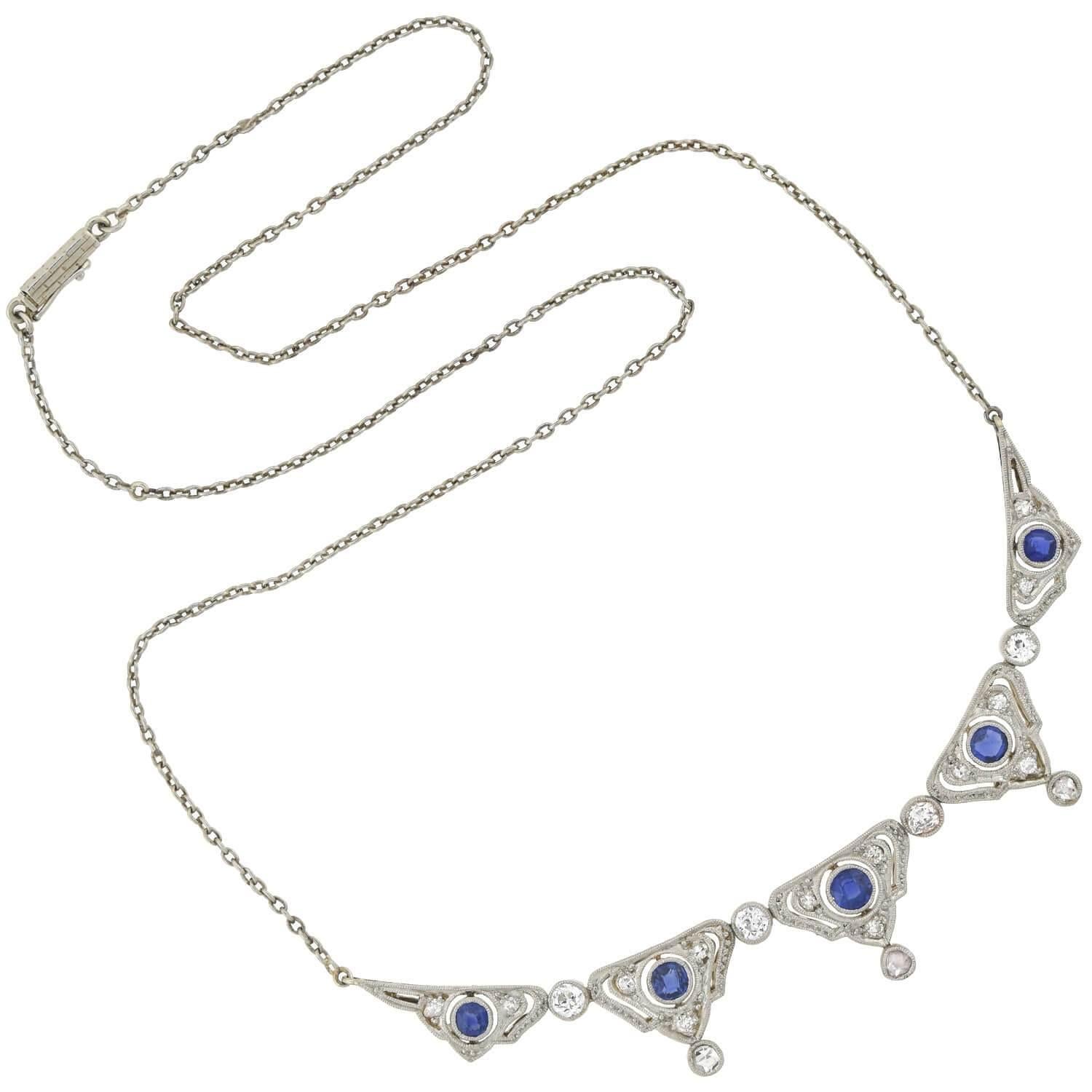 A stunning diamond and sapphire necklace from the Edwardian (ca1910s) era! Crafted in platinum topped 14kt yellow gold, this beautiful piece features five triangular links which alternate with four glittering Full Cut diamonds. Each triangular link