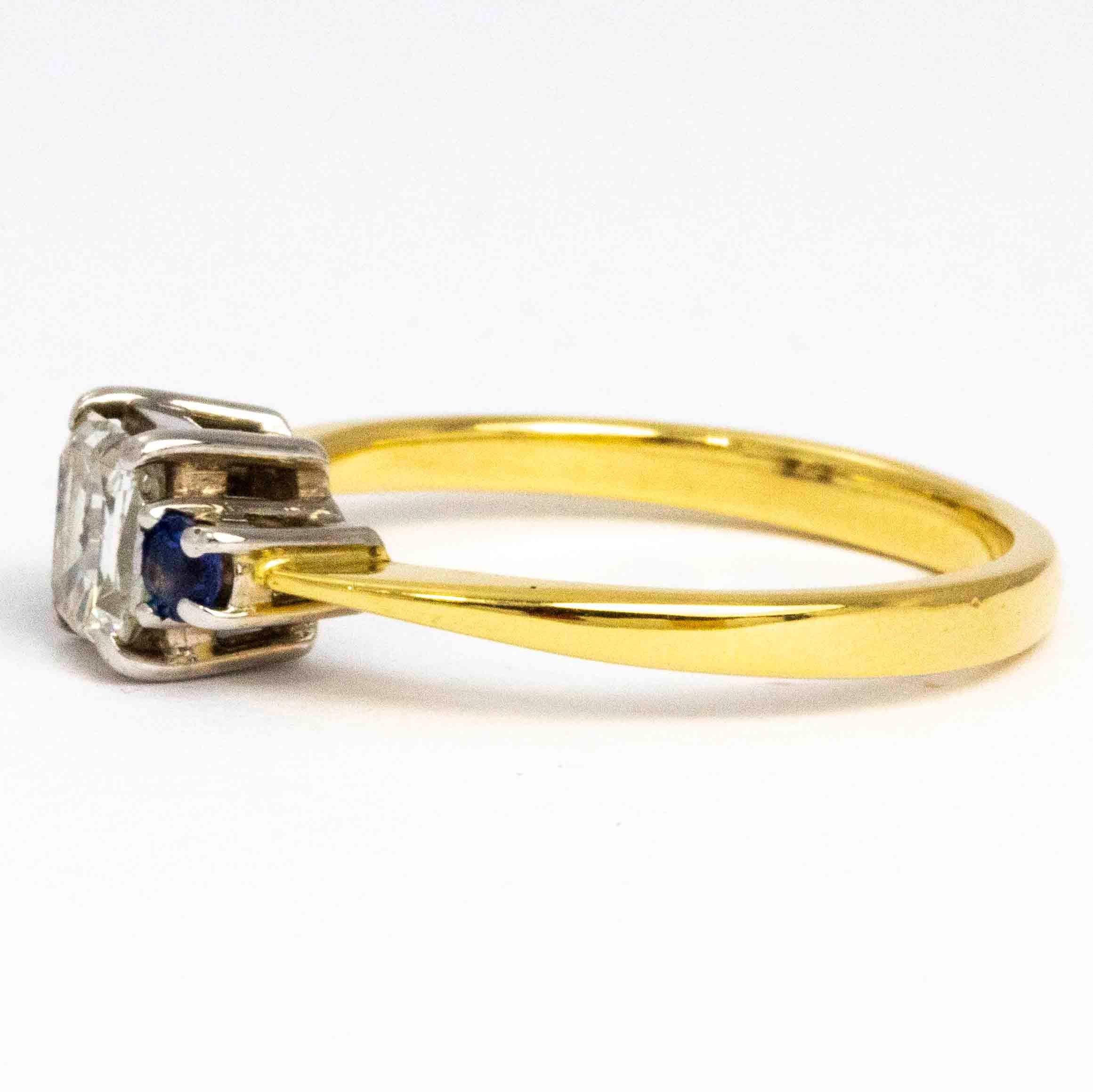 The bright sparkling emerald cut diamond at the centre of this three stone ring is beautiful and complemented perfectly by a sapphire either side. The stones are set in platinum and the band is modelled in 18ct gold. Measuring 65pts, the diamond is