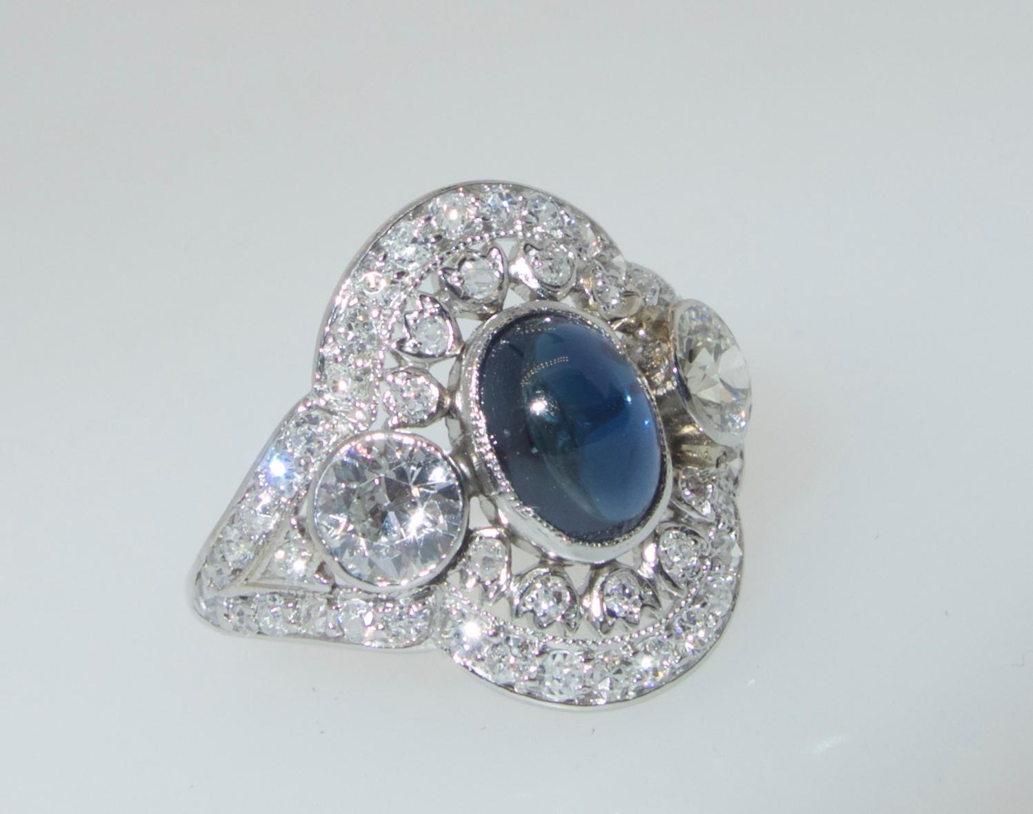 Edwardian platinum ring with fine white diamonds accenting the center fine blue natural, unheated vibrant sapphire.  The European cut diamonds  are white, (H), and very slightly included (VS).  The center sapphire is unheated, a vibrant deep blue