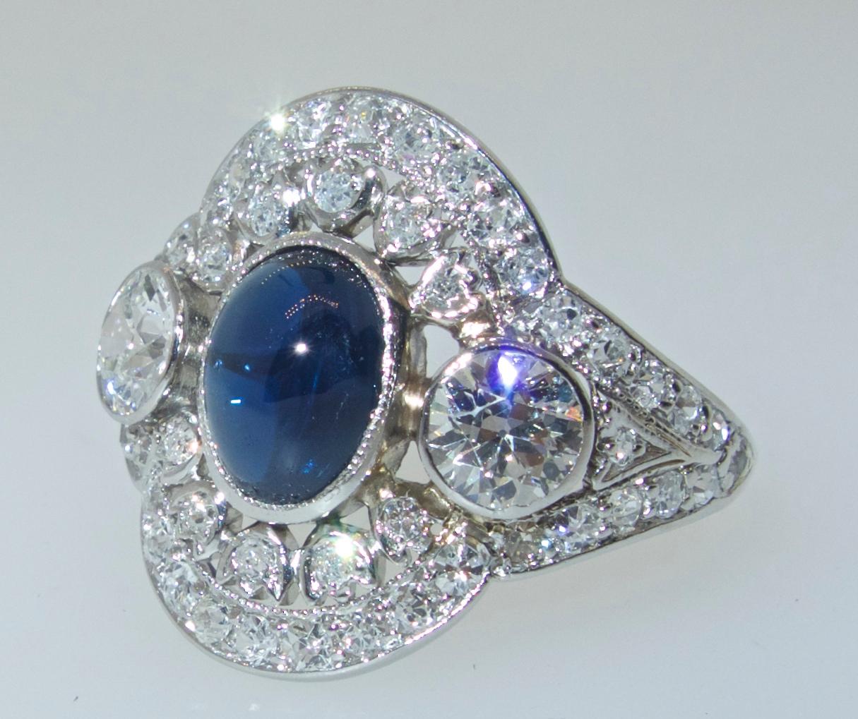 Edwardian platinum ring with fine white diamonds accenting the center fine blue natural, unheated vibrant sapphire.  The European cut diamonds  are white, (H), and very slightly included (VS).  The center sapphire is unheated, a vibrant deep blue