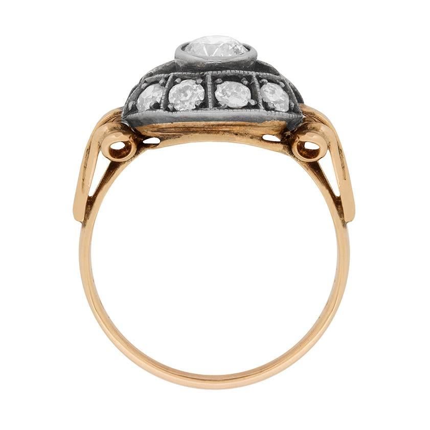 This eye-catching Edwardian era diamond cluster ring was handmade in period style during the early 1900s.

It features a curving quartet of old cut diamonds in box and claw mountings to the top and bottom of a larger, centrally set diamond, creating