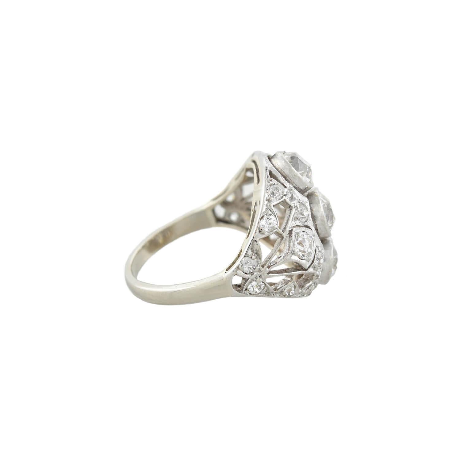 A striking handmade diamond dome ring from the Edwardian (ca1910s) era! Crafted in 14kt yellow gold and topped in platinum, this diamond ring adorns three Old Mine Cut diamonds in a row at its center. The ring features light-catching milgrain and a