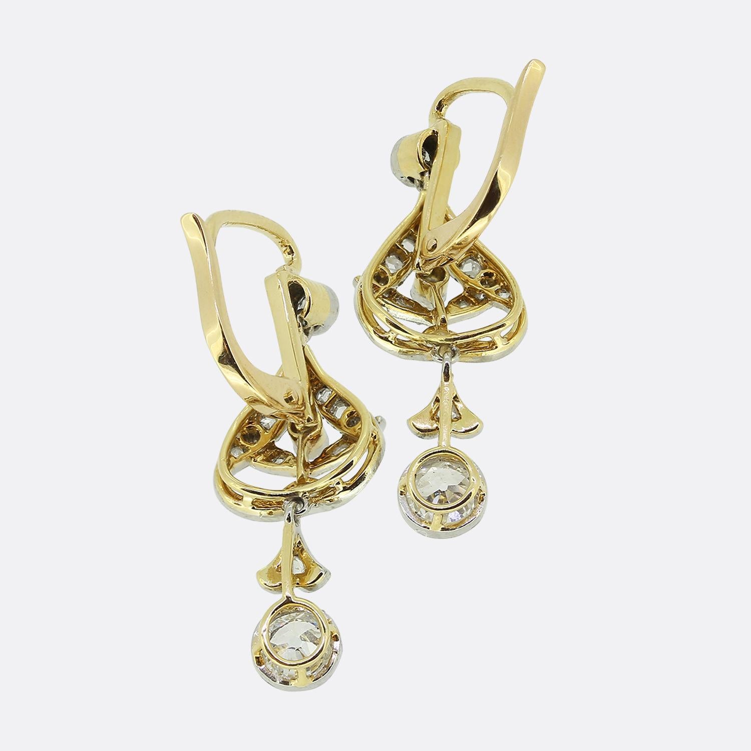 Here we have a fabulous pair of diamond drop earrings dating back to the Edwardian period. Both identical antique pieces showcases an open foliated design with fine milgrain set channels filled with rose cut diamonds. This frame is surmounted by a