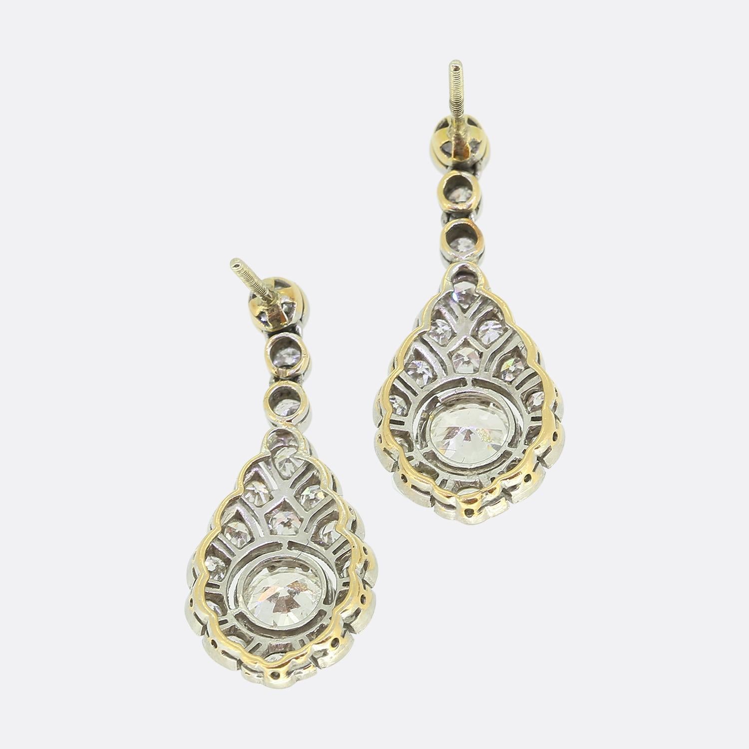 Here we have a stunning pair of drop earrings crafted from 18ct gold and platinum during the Edwardian period. Each earring features a surmounting trio of round faceted old cut diamonds in a vertical line formation which suspends a dazzling array of
