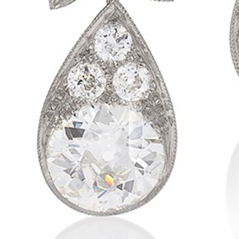 A pair of Edwardian platinum drop earrings with diamonds. The earrings have a delicate graduating drop of four stones and a delicate downward facing leaf motif garnishing the top of a dramatic tear drop housing a 2.00 carat Old European Cut diamond.