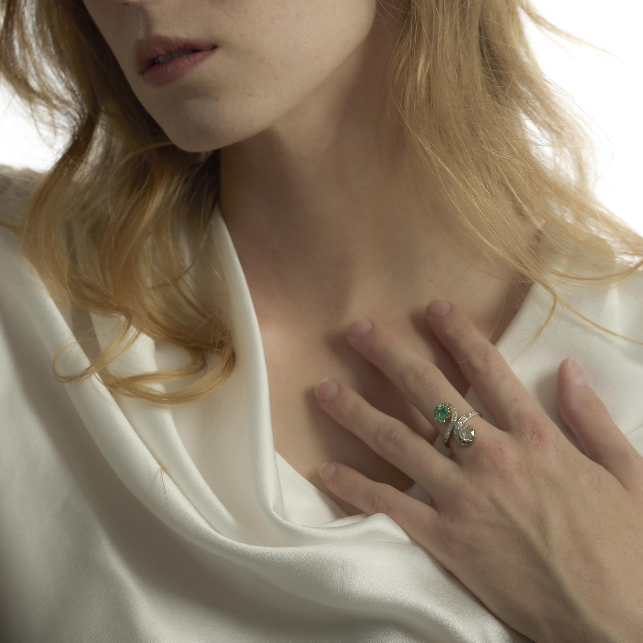 This Edwardian Toi Et Moi ring from the 1910’s pairs a 1.10 carat old European cut diamond with a vibrant .90 carat cushion cut emerald, symbolizing the union of two souls. Surrounded by a halo of old mine and rose cut diamonds, the design radiates