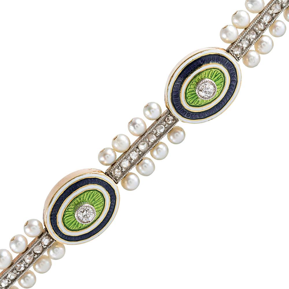 Beautifully detailed and delicate, the bracelet is made of platinum over 18k yellow gold and fashioned of enameled oval sections, each dotted in the center with a brilliant white diamond, connected by bridges of rose cut diamonds and seed pearls.