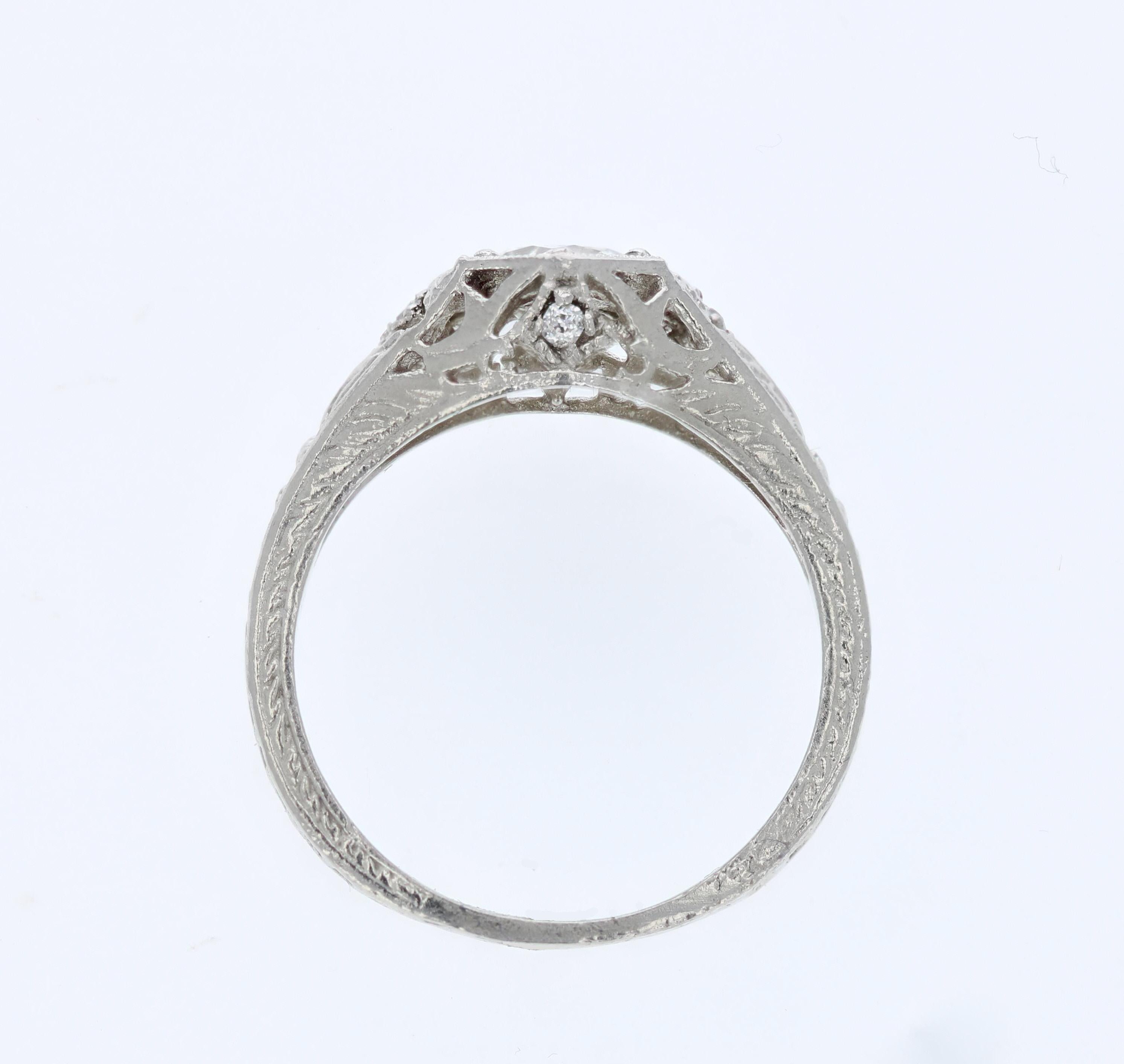 A gleaming white, 0.59 carat old European diamond sits in a unique hexagon shaped setting in this Edwardian engagement ring. Detailed engraving and fine millegrain adorn the platinum setting along with 4 round accent diamonds. The center stone comes