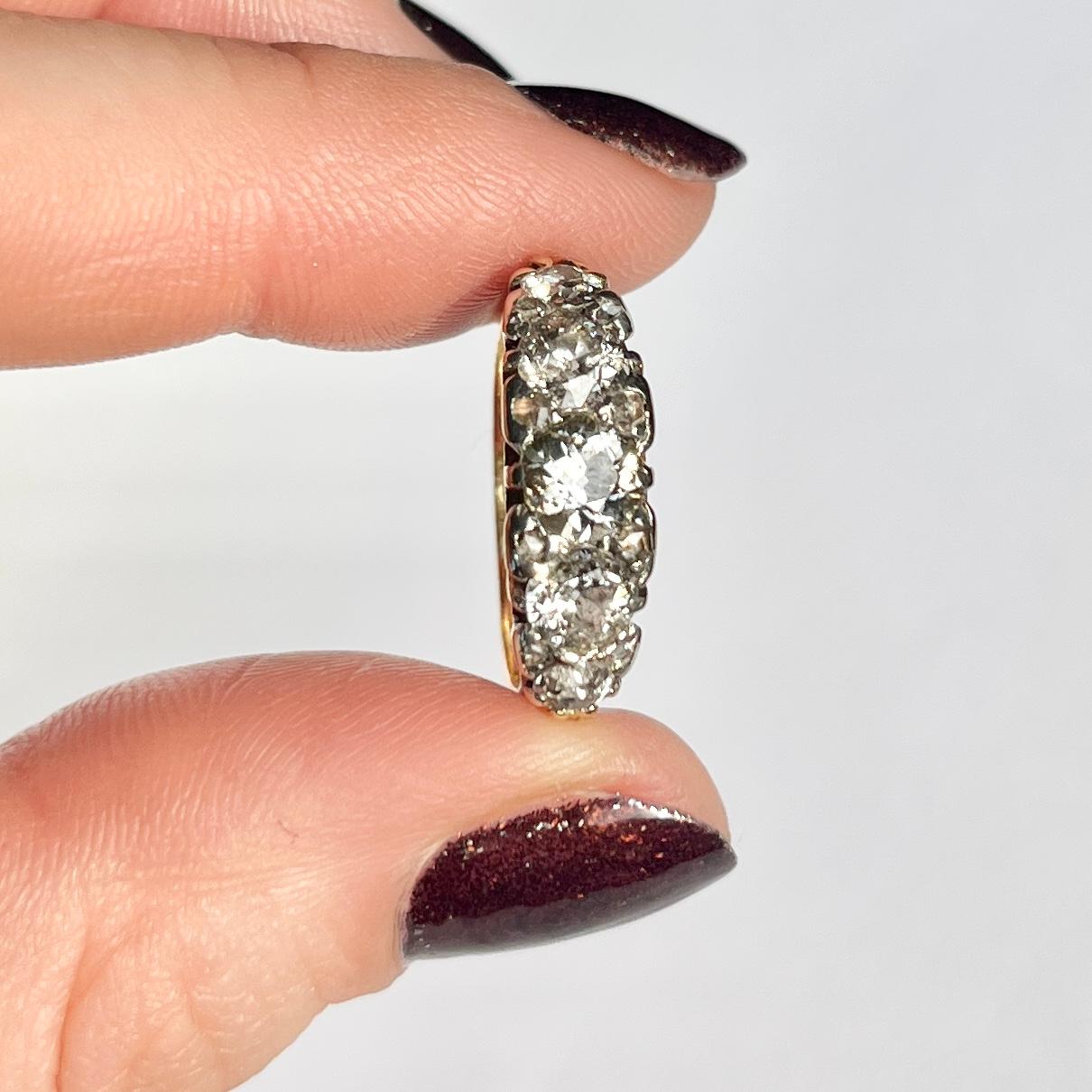 Five glistening diamonds sit fabulously within a decorative scroll setting modelled in 18ct gold. The central stone measures 50pts, the next size measure 35pts each and the smallest stones measure 10pts each. Either side of each diamond are pairs of