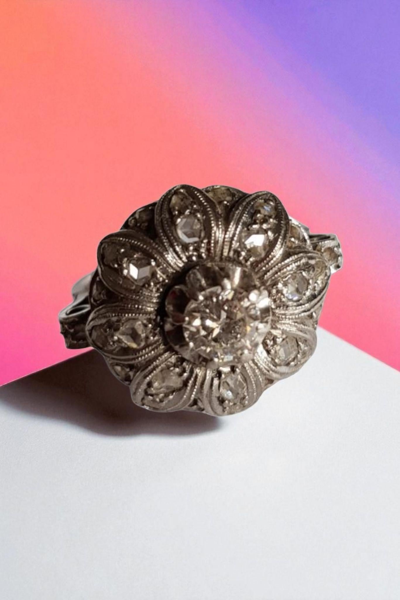 Exquisito anillo floral en racimo de la época eduardiana, magistralmente elaborado a mano hacia 1910. Esta pieza romántica e intrincadamente detallada presenta un diamante central de talla europea antigua, con un peso aproximado de 0,30 a 0,35