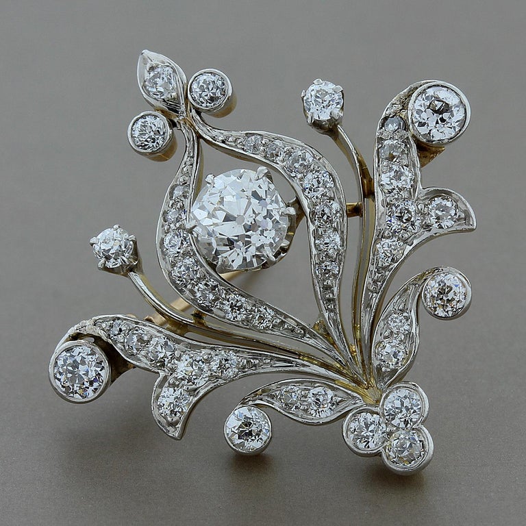 An Edwardian diamond brooch from the early 1900's featuring a 0.80 carat European cut diamond, complemented by 1.05 carats of European cut diamonds around the brooch. Set in 14K yellow gold with a platinum top. 
Dimensions: 1-3/16 inches x 1-1/8