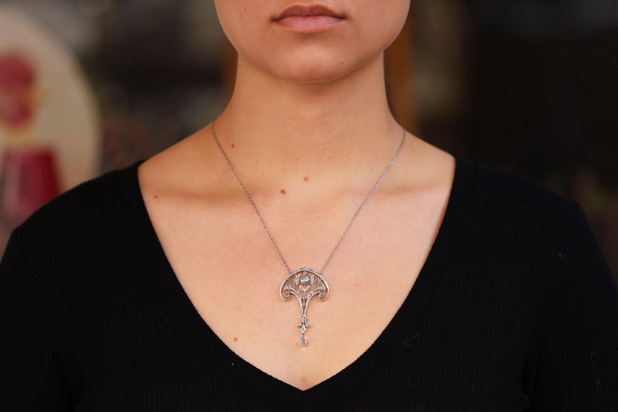 Un'elegante collana edoardiana con ciondolo, perfettamente realizzata in platino, che drappeggia deliziosamente il tuo collo. La filigrana di questa lavalière Belle Epoque crea un motivo floreale sinuoso e curvilineo contrastato da una struttura