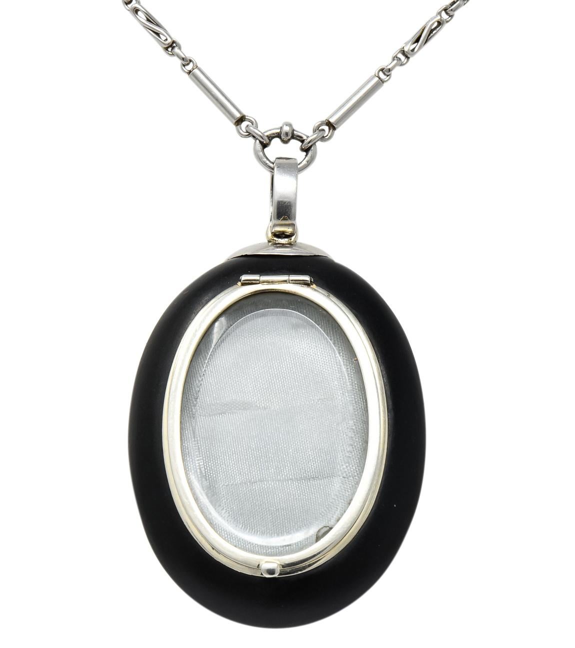 Centering a round natural pearl measuring 6.0 mm, white in body color with silver overtones and good luster

Surrounded by hollow, oval cabochon onyx measuring approximately 1 5/8 x 1 3/16 inches, opaque and matte black in color

Back of onyx has