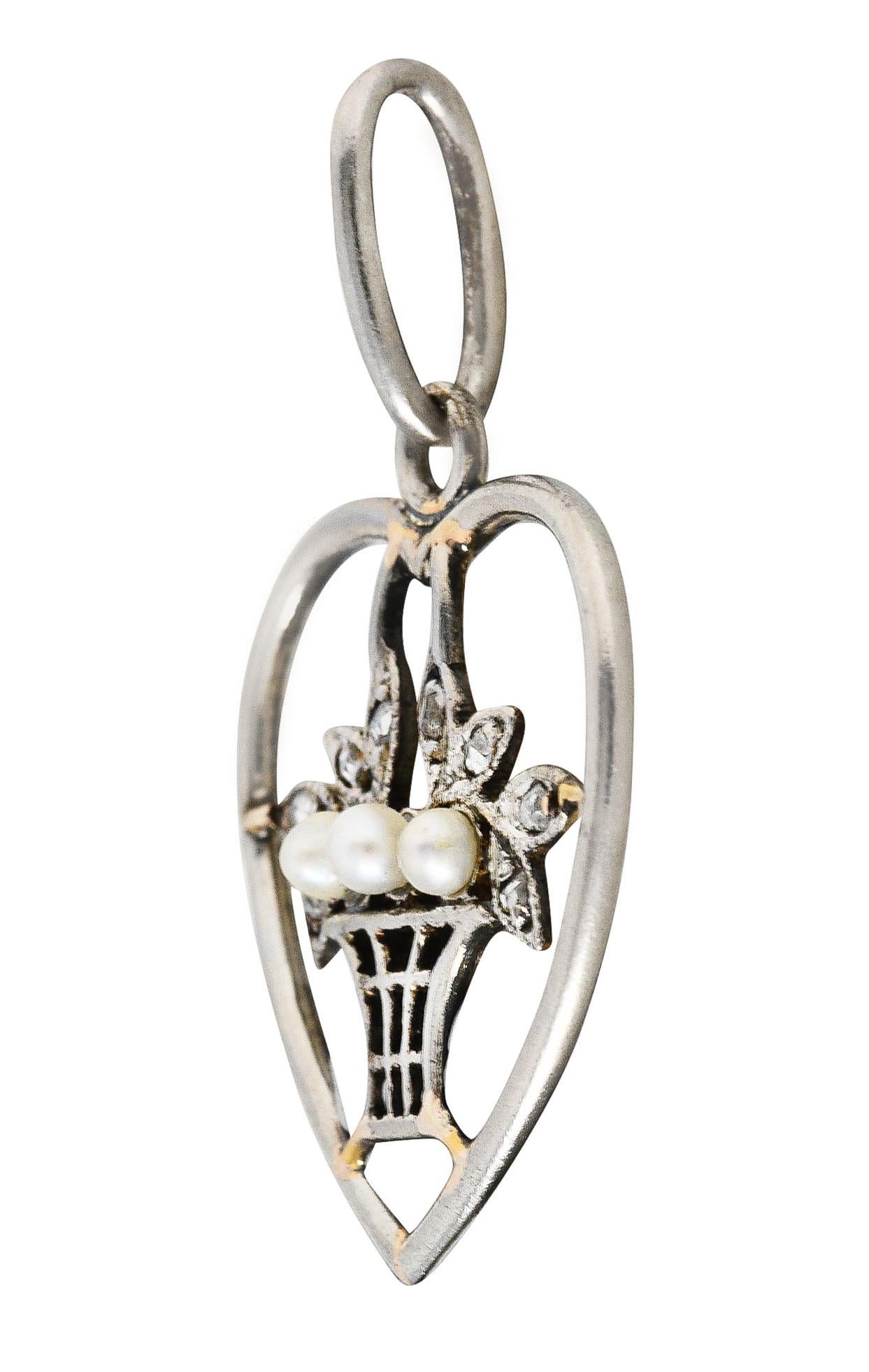 Giardinetto style charm features a striated basket overflowing with foliate and a heart surround. Accented by rose cut diamonds and featuring three 2.0 mm pearls. White in body color with very good luster. Tested as platinum-topped 18 karat gold.