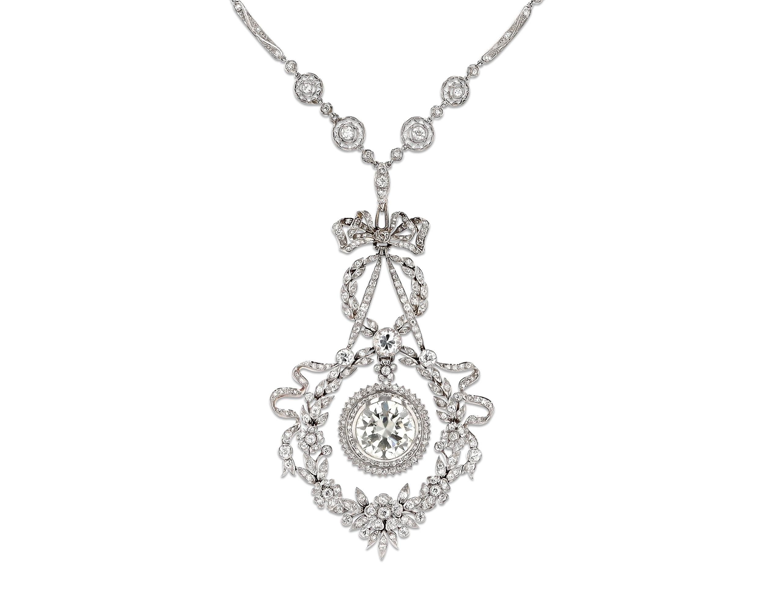 Adorned by diamonds totaling approximately 13.60 carats, this Edwardian-style necklace by J.E. Caldwell exhibits a classic elegance. A round white diamond weighing approximately 6.85 carats rests at its center; it is surrounded by floral vignettes