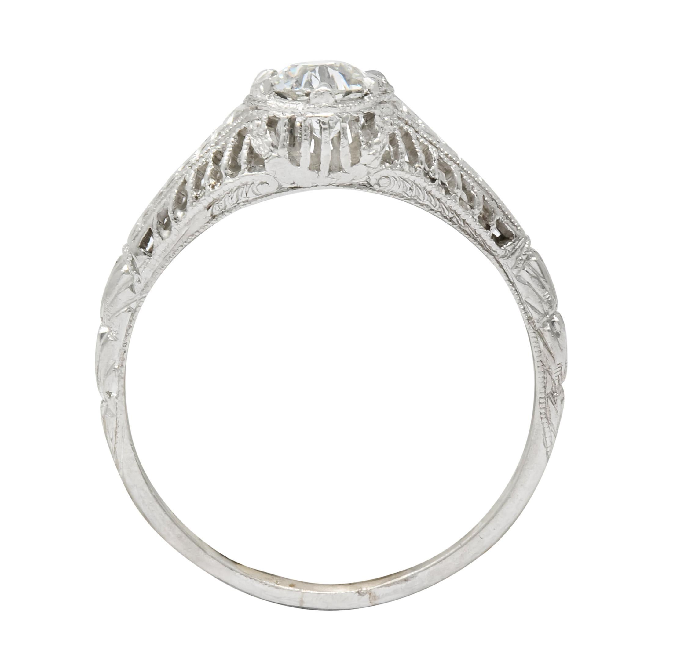 Centering a transitional cut diamond weighing approximately 0.50 carat, J color and VS clarity

Talon set low in mounting with pierced striated gallery and milgrain detail

Flanked by linear foliate motif flowing to deeply engraved shoulders

With