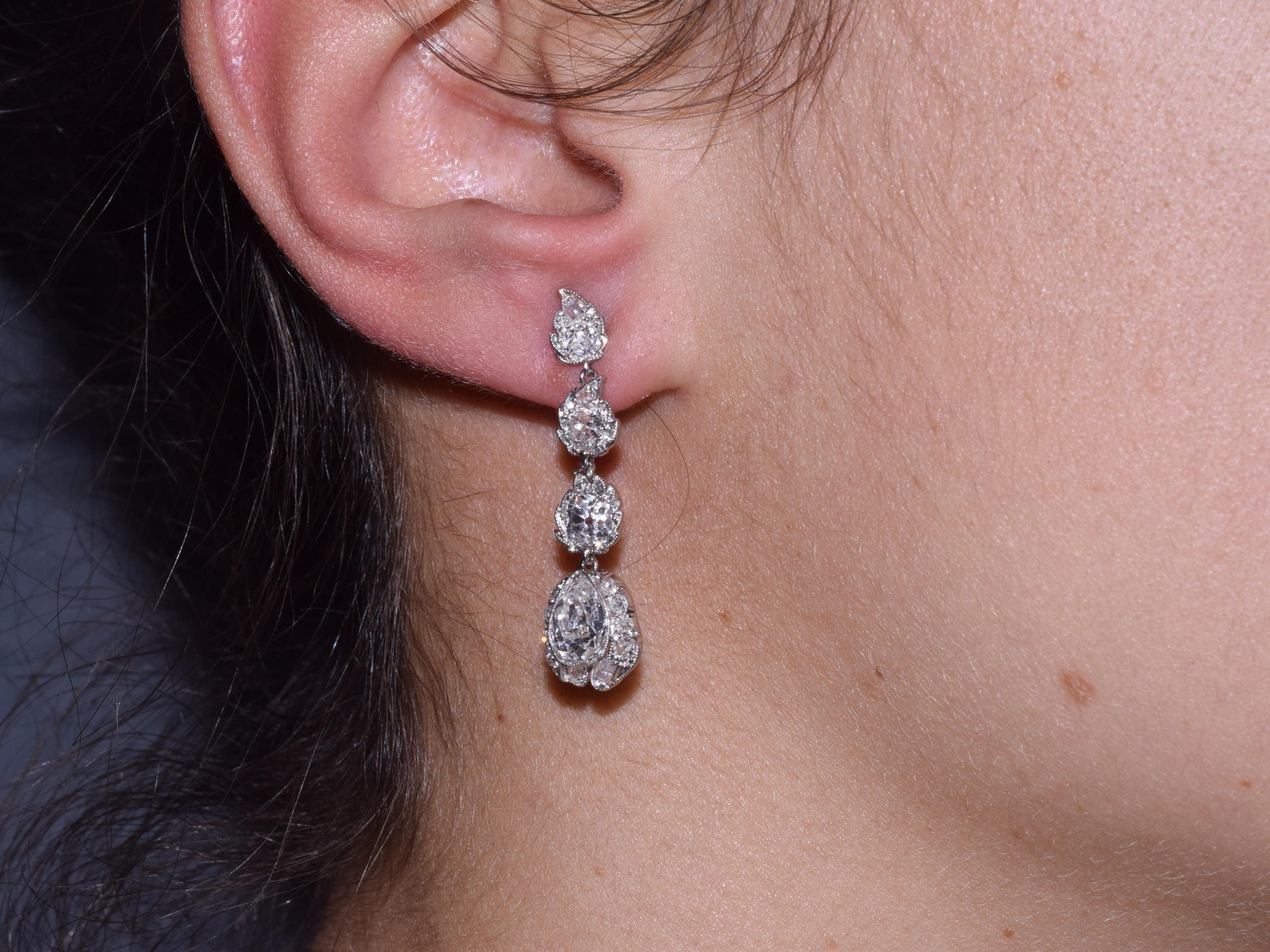 A total of approximately 4.25 carats of old mine diamonds form the leaves and buds of a stylized floral motif set in platinum. The earrings measure 1-3/8 inches in length and 3/8 inch at the widest point.