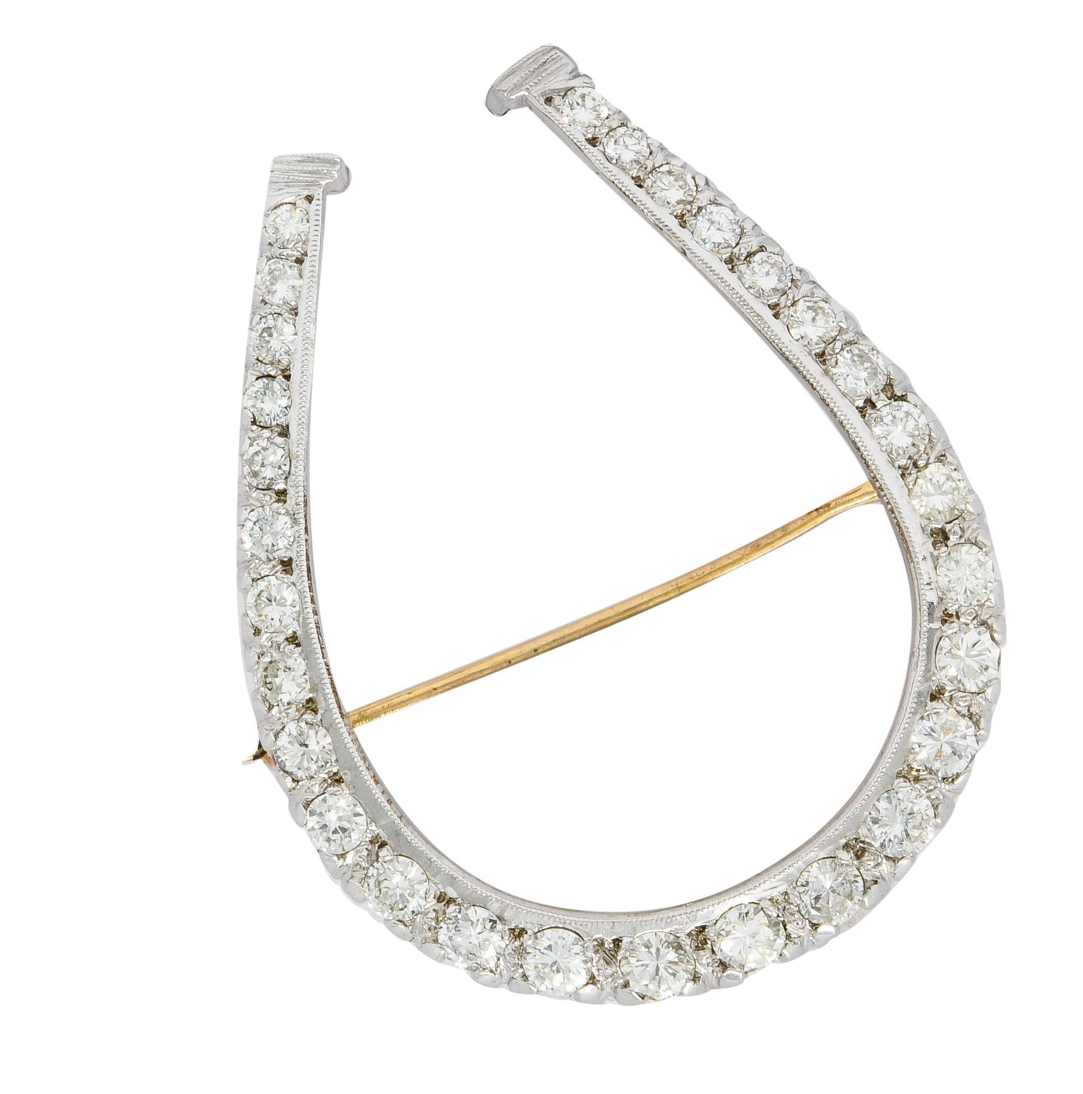 Brooch is designed as a substantially sized horseshoe with a stylized fishtail gallery

Set throughout by round brilliant cut diamonds weighing approximately 2.45 carats; G to J color with VS to SI clarity

Accented by milgrain and a scalloped