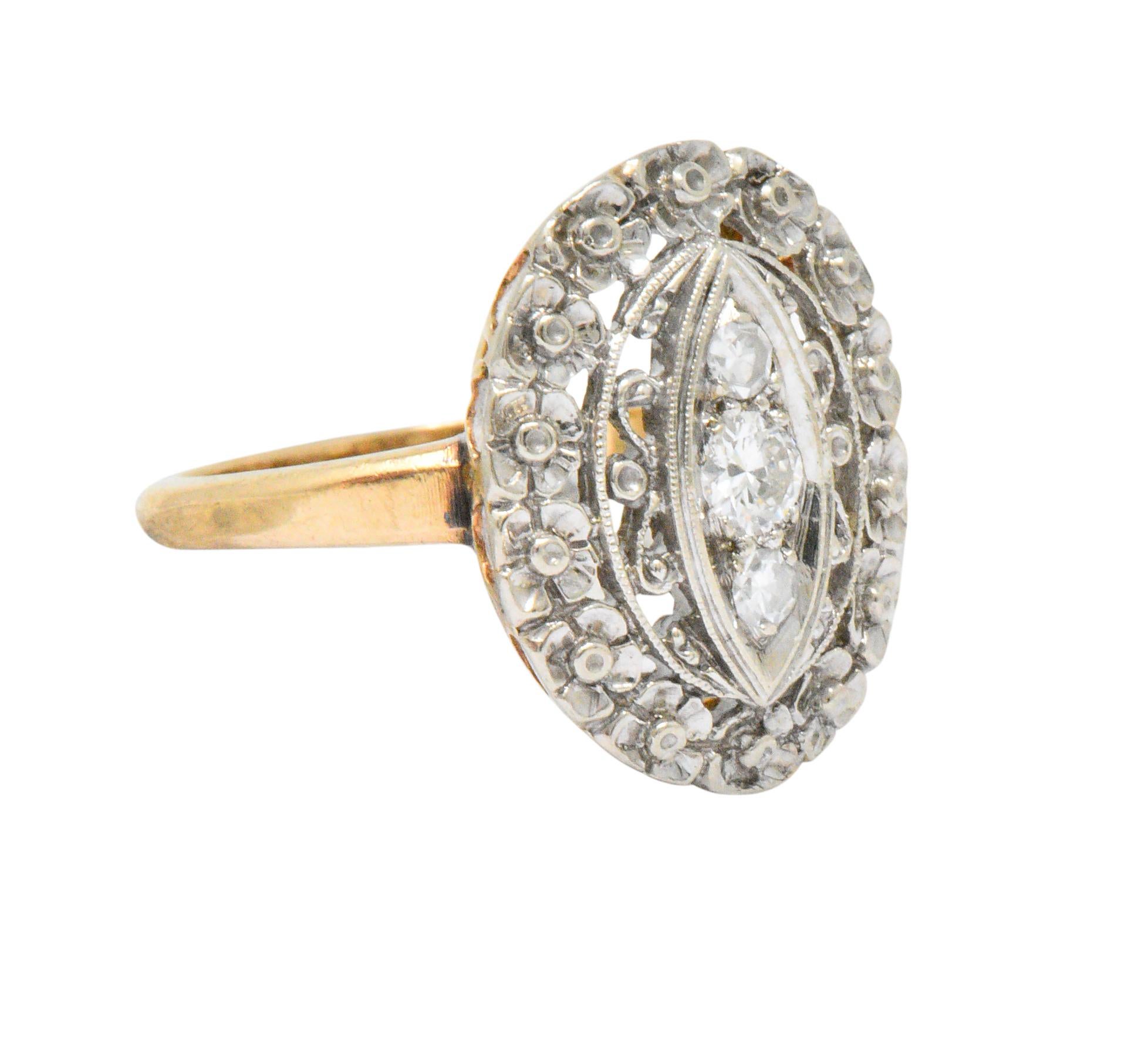 Centering a round brilliant cut diamond with single cut diamonds above and below, three diamonds total, weighing approximately 0.20 carat total, eye-clean and white 

Lovely pierced floral and scrolling motif surround

CTW: 0.20

Ring Size: 6 &