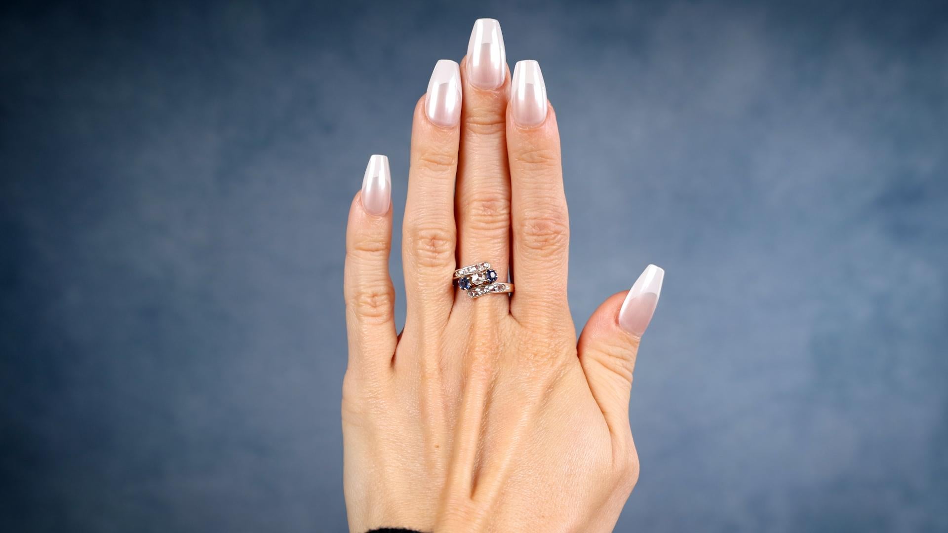 Ein Edwardian Diamant Saphir 18k Rose Gold Silber Bypass Ring. Mit neun Diamanten im Rosenschliff mit einem Gesamtgewicht von 0,25 Karat, Farbe G-H, Reinheit SI. Akzentuiert durch zwei Saphire im Kissenschliff mit einem Gesamtgewicht von 0,35 Karat.