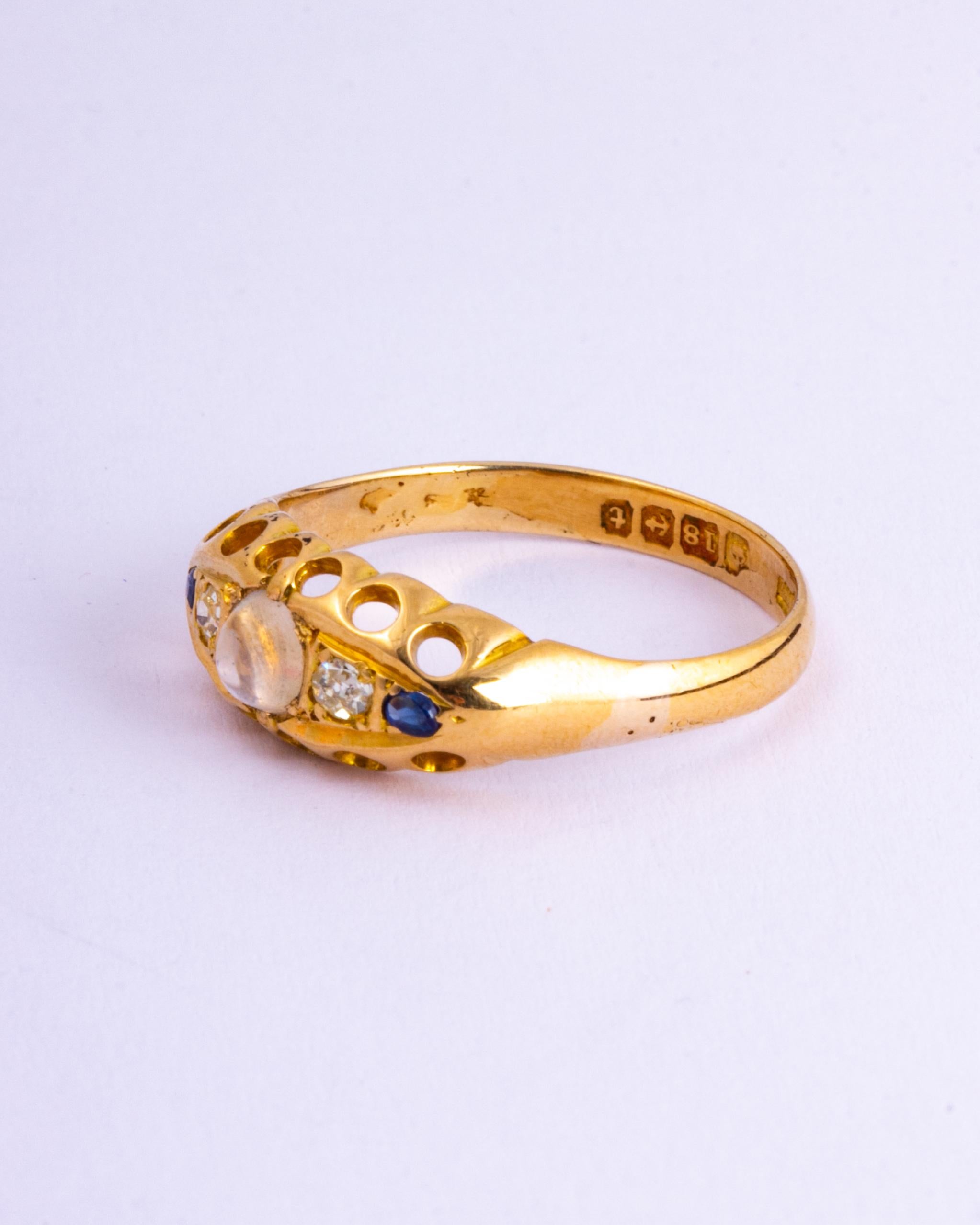 The ring holds two diamonds which total 8pts and there are also sapphire points on the outer edge. At the centre there is a moonstone which sits proud above the other stones. The ring is modelled in 18ct gold and the stones are set in a boat shaped