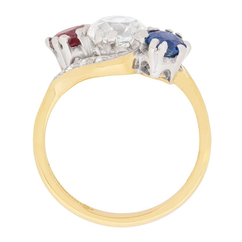 This stunning ring features a 1.44 carat old cut diamond in the centre, highlighted by two beautiful gemstones with side; one sapphire and one ruby. The diamonds is a hand cut stone and estimated as G in colour and VS1 in clarity. The sapphire is a